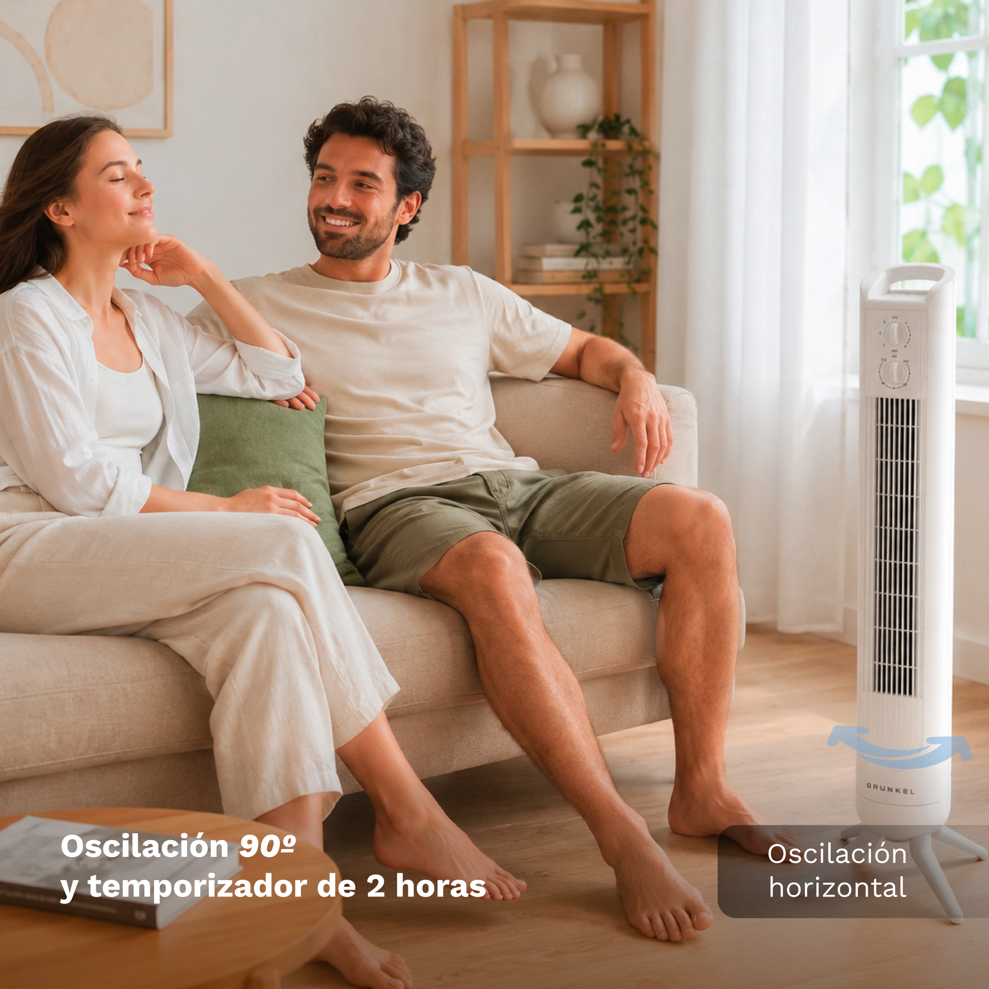 Una pareja sonriente se relaja en un sofá en una sala luminosa junto a un ventilador de torre blanco alto.