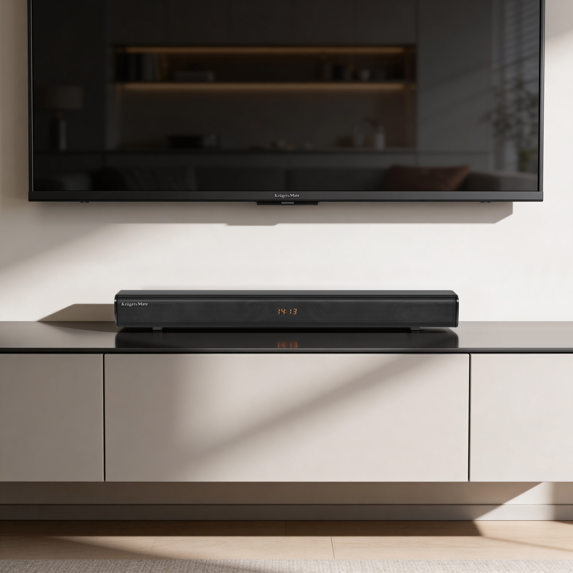Dluga czarna soundbar na jasnej szafce, powyzej duzy telewizor.