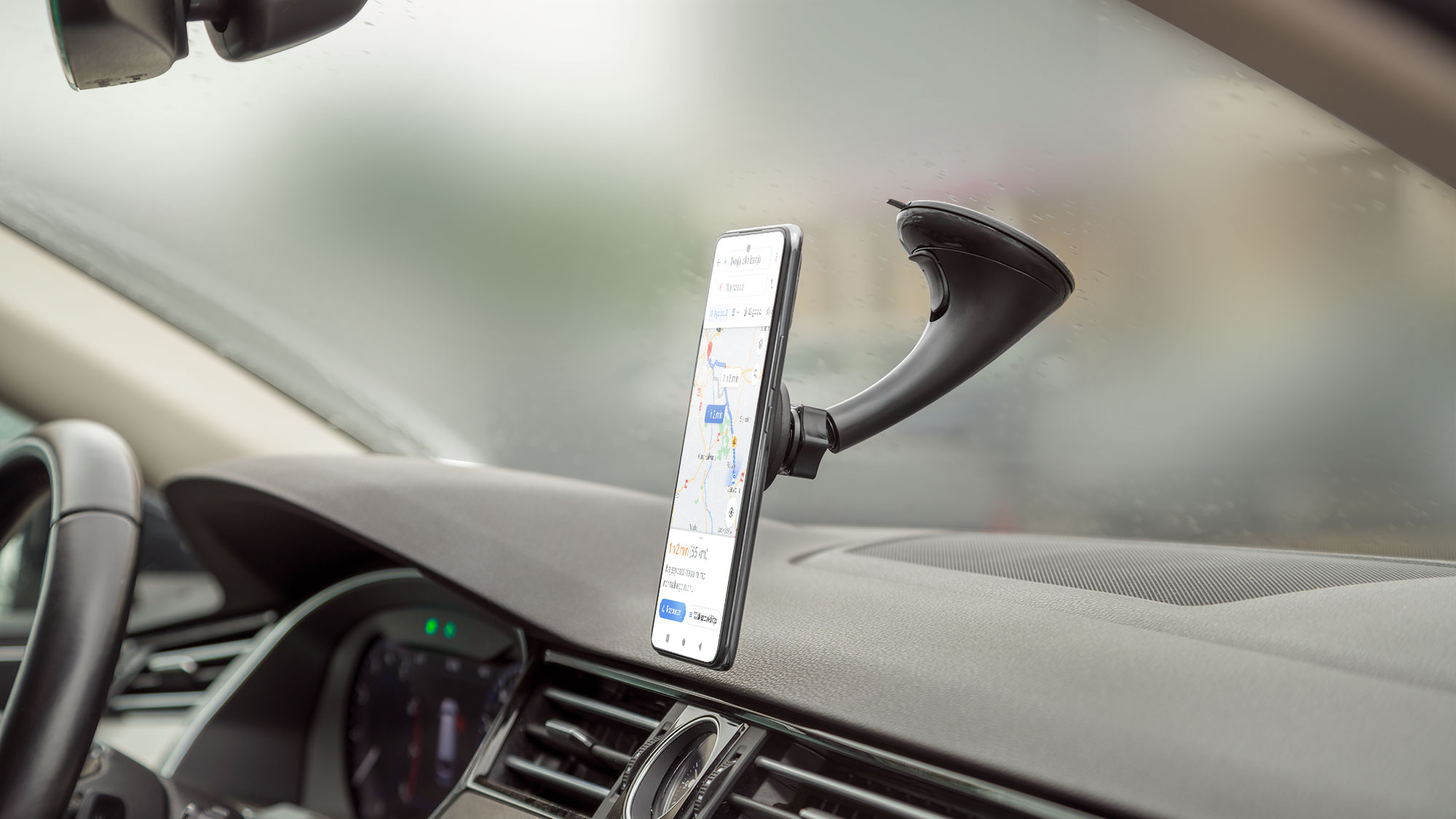 Smartfon z nawigacją GPS jest zamontowany w uchwycie na desce rozdzielczej samochodu.