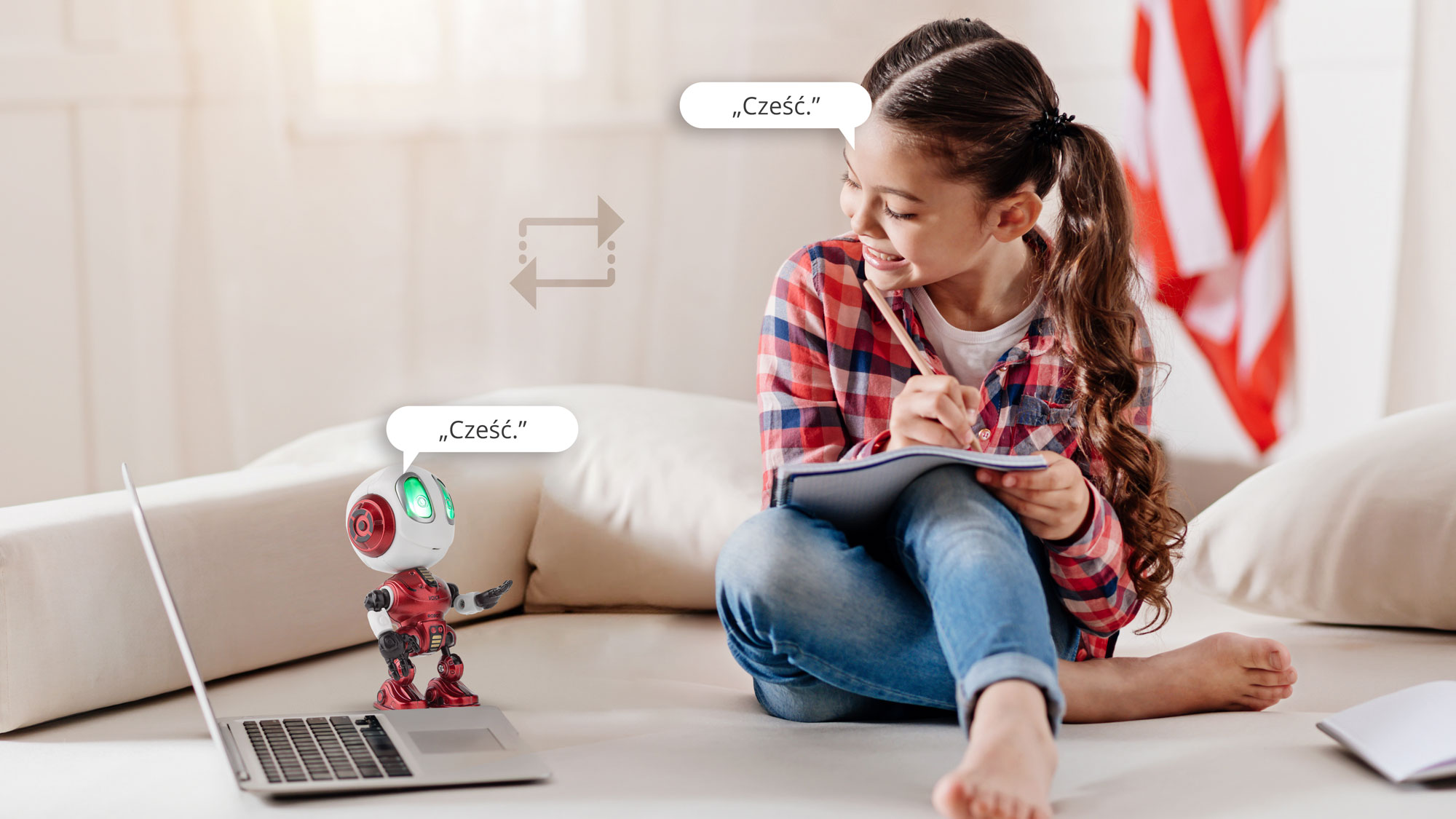 Młoda dziewczynka siedzi na kanapie, uśmiecha się i pisze w notesie obok laptopa oraz małego czerwonego robota.