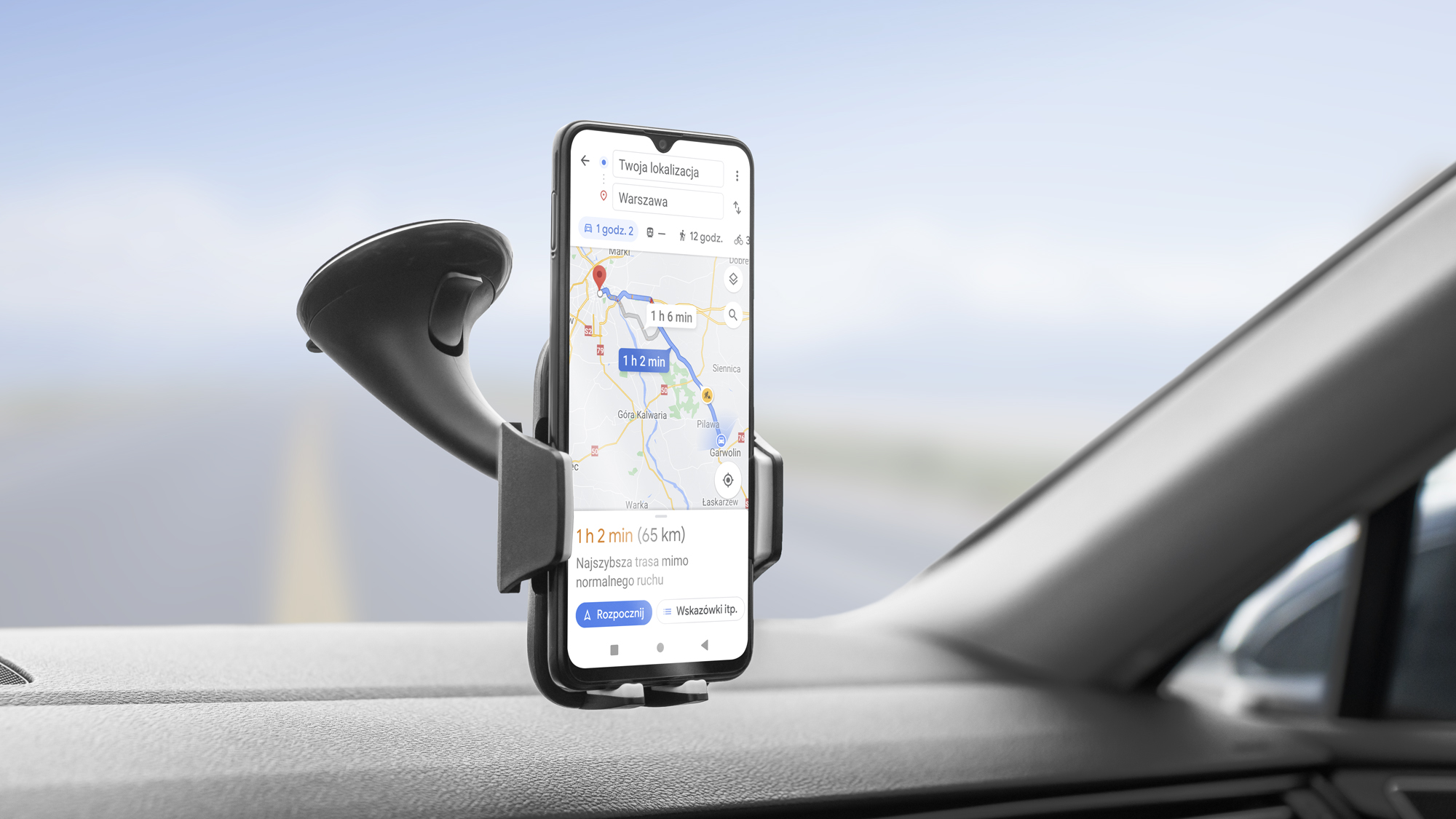 Smartfon z aplikacją nawigacyjną w uchwycie samochodowym na desce rozdzielczej.