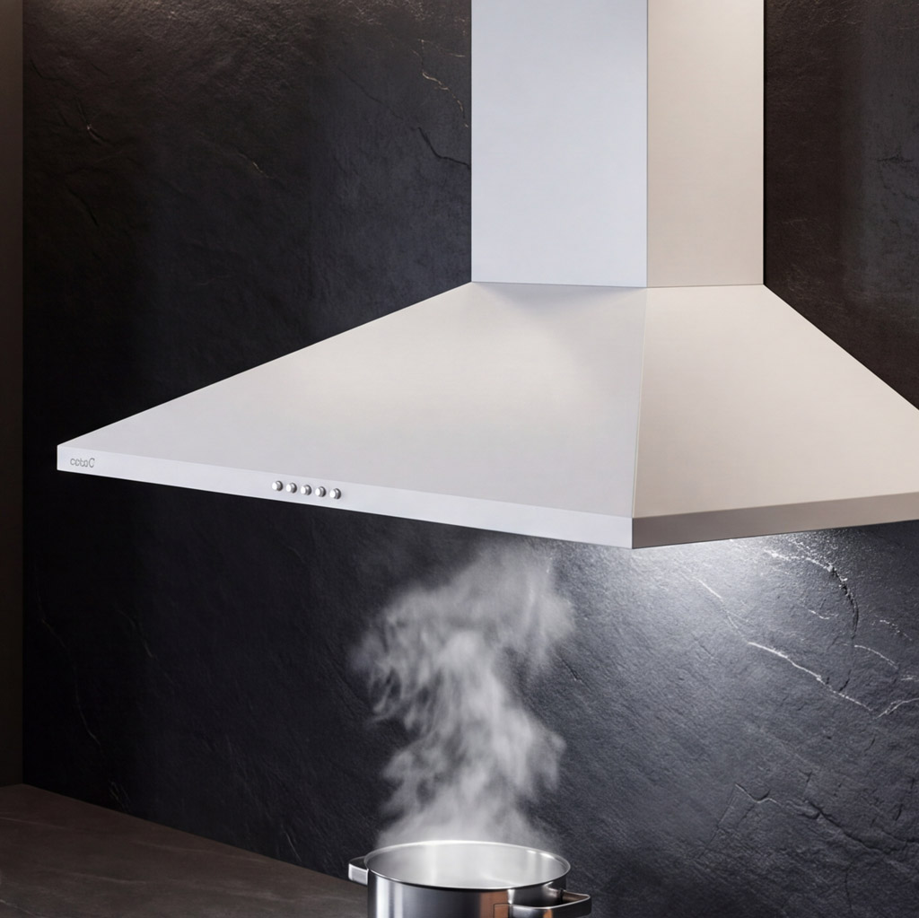 Una campana extractora blanca sobre una olla humeante ante una pared oscura.