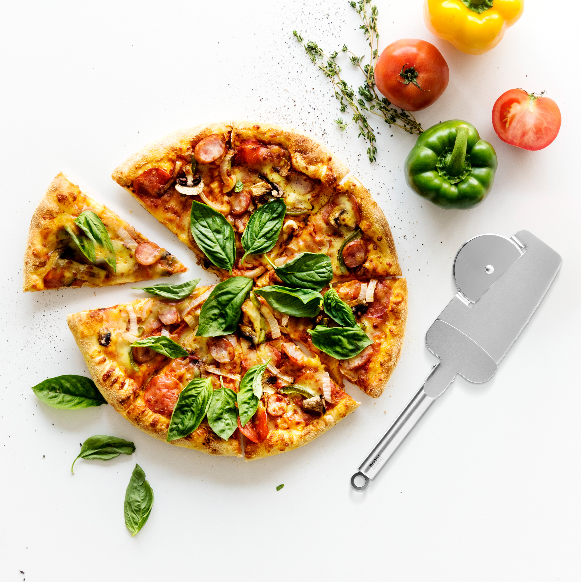 Pizza z bazylią, warzywami i krojem na białym stole.