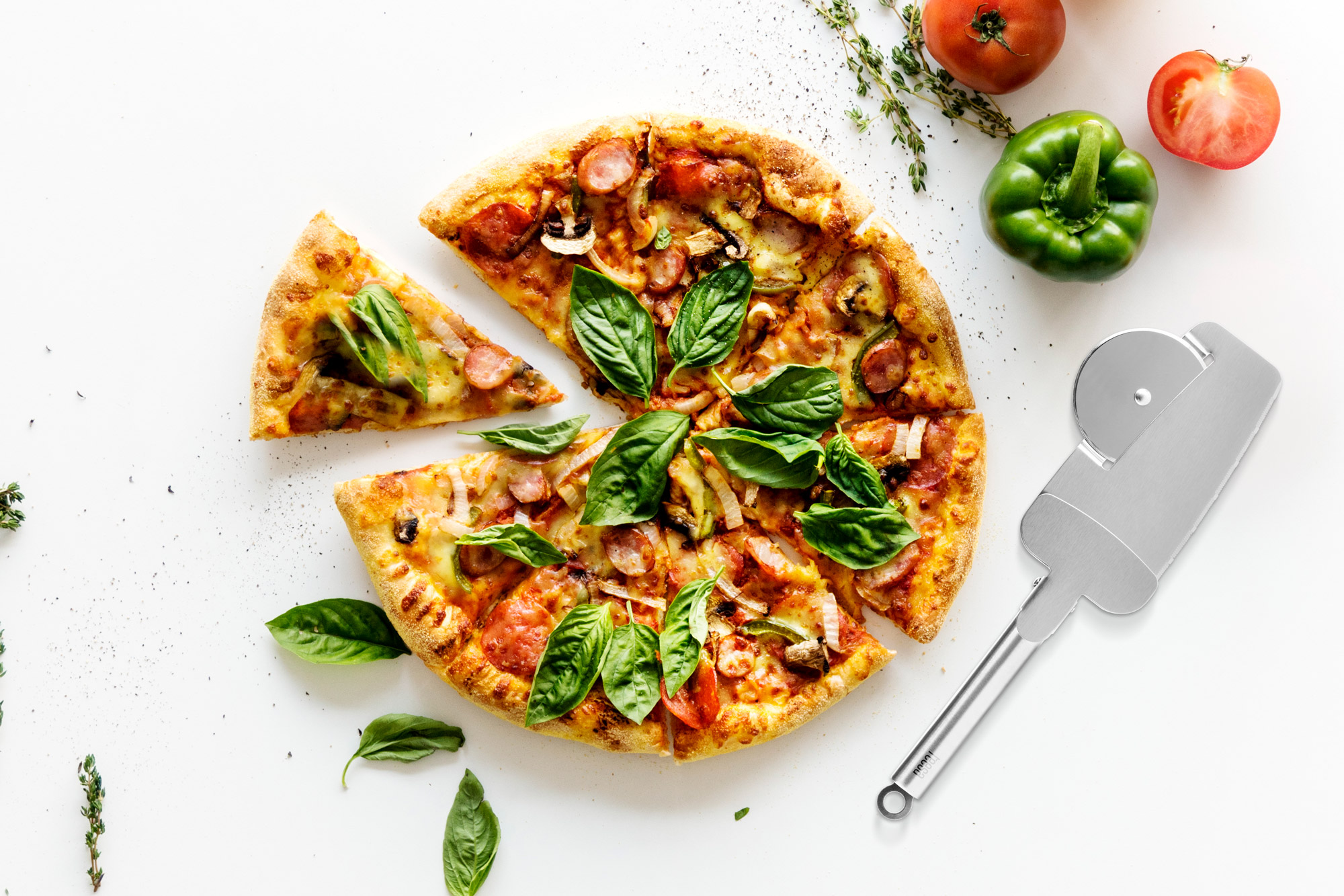 Pizza ze świeżą bazylią, pomidorami, papryką i nożem do pizzy na białym stole.