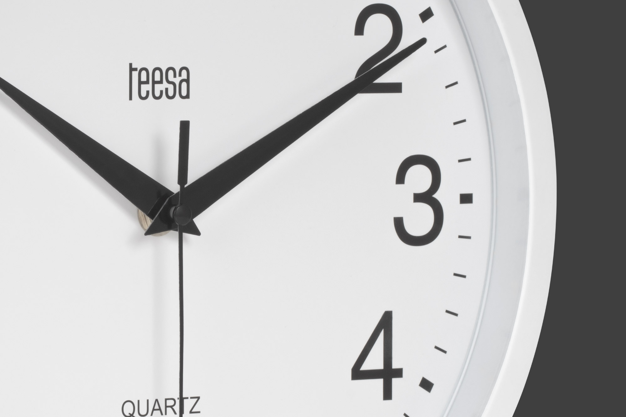 Zbliżenie białego zegara ściennego Teesa Quartz z czarnymi wskazówkami i cyframi.