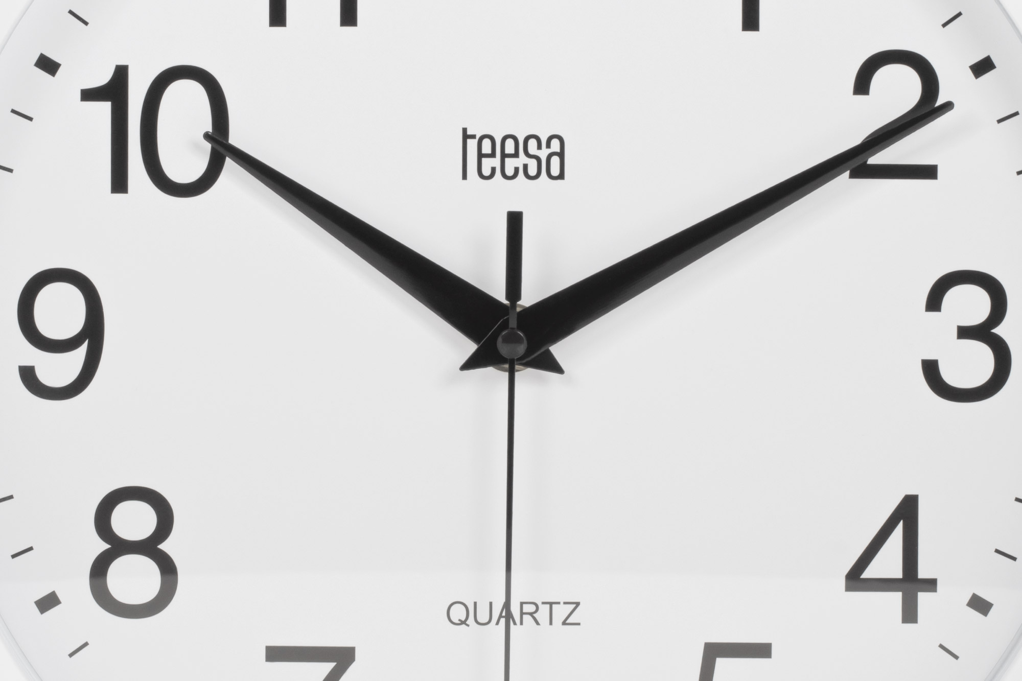 Zbliżenie białej tarczy zegara kwarcowego Teesa z czarnymi cyframi i wskazówkami.