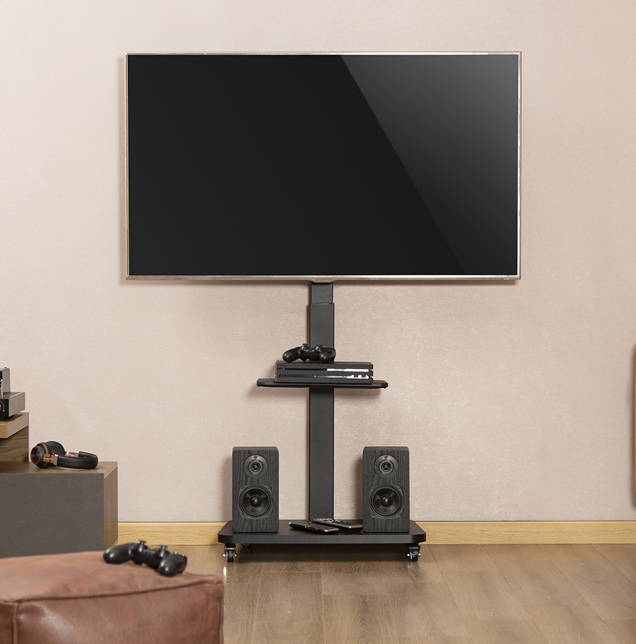 Un televisor en un soporte negro con altavoces, consola y control remoto contra una pared beige.