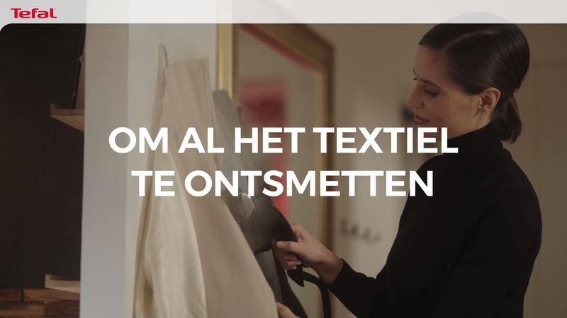 Une femme utilise un défroisseur vapeur à main sur des vêtements.