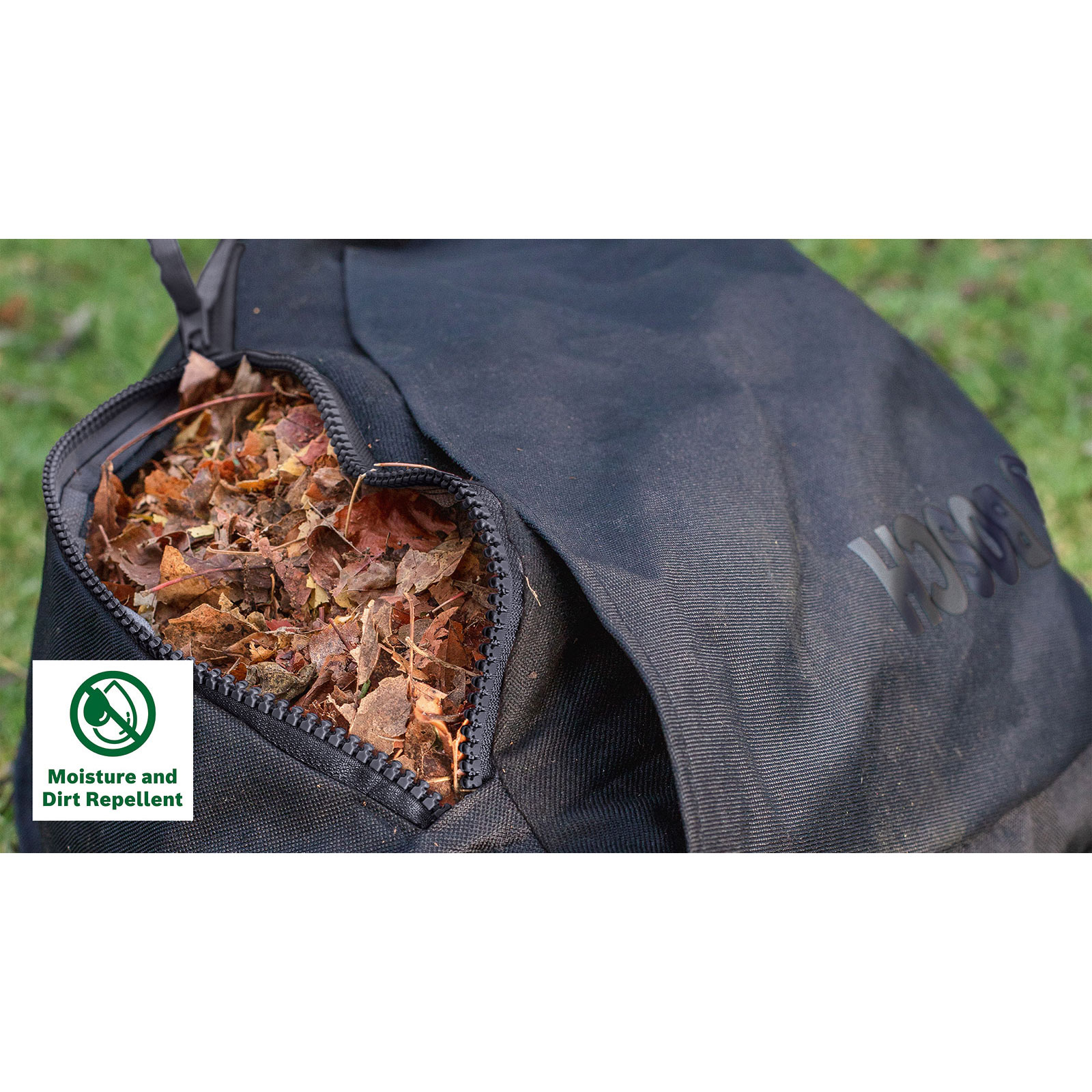 Ein schwarzer Rucksack gefüllt mit trockenen Herbstblättern, im Hintergrund grüne Wiese.