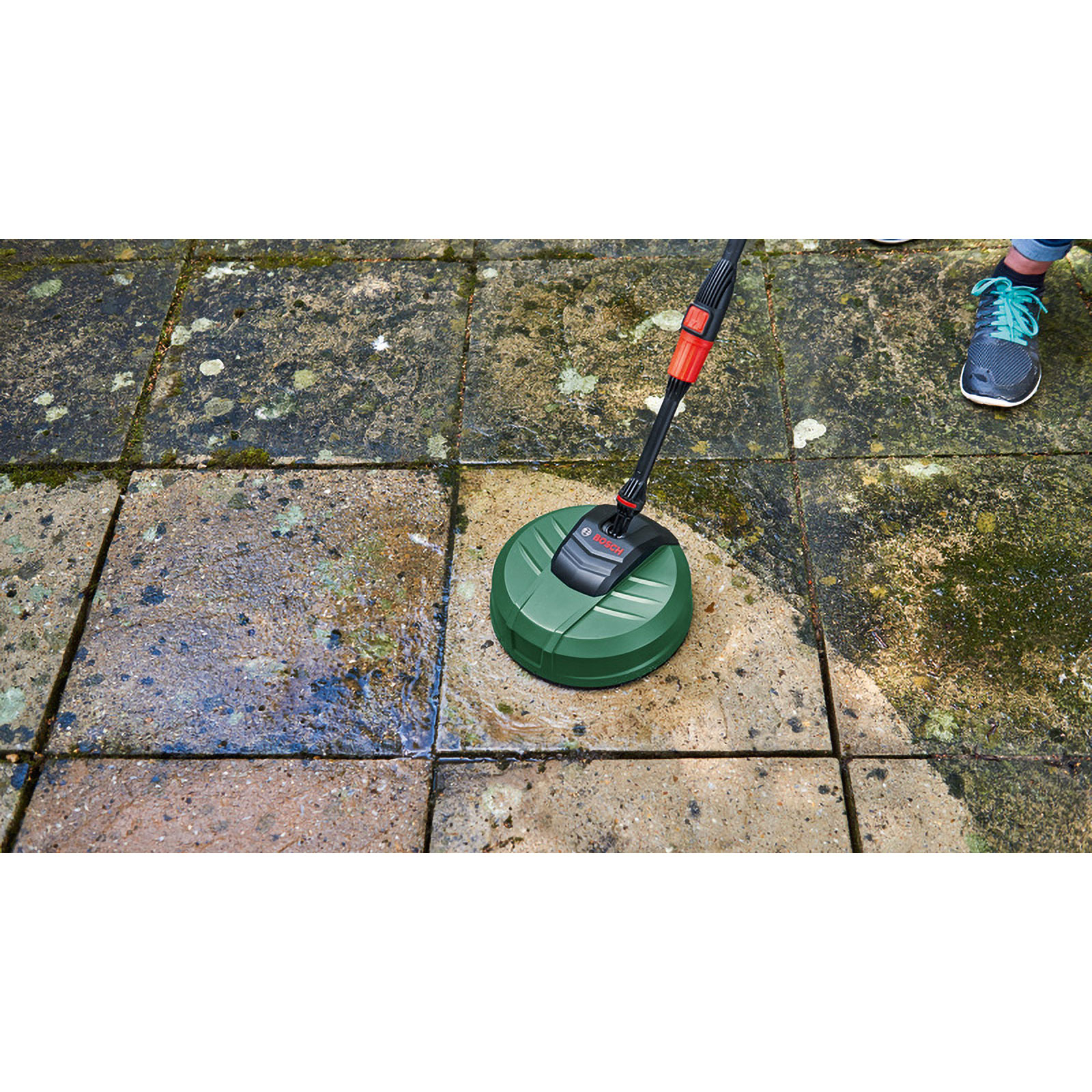 Ein grüner Flächenreiniger reinigt schmutzige Steinplatten im Garten.