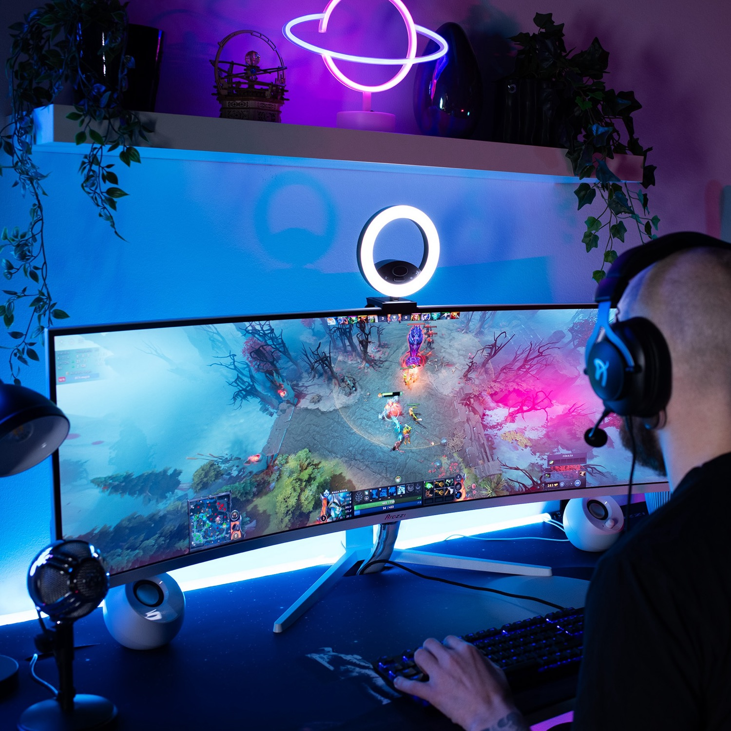 Ein Gamer mit Kopfhörern spielt in einem bunten, neonbeleuchteten Zimmer ein Videospiel auf einem breiten Curved-Monitor.