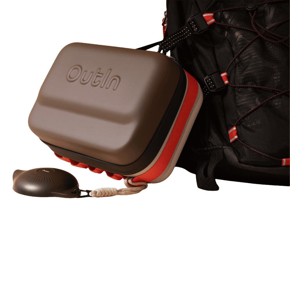 Ein braunes Outin-Etui mit rotem Reißverschluss ist an einem schwarzen Rucksack befestigt.