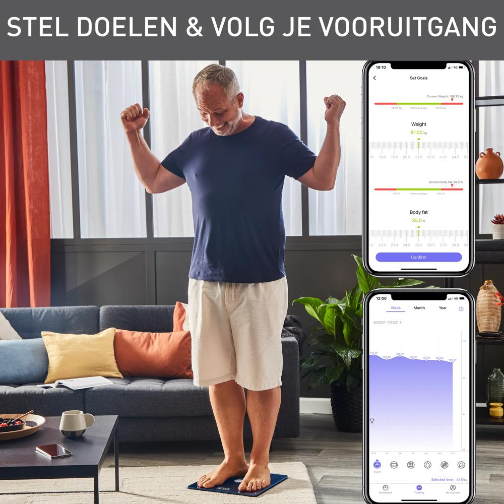 Un uomo sorride su una bilancia in soggiorno, con due smartphone che mostrano app di fitness.