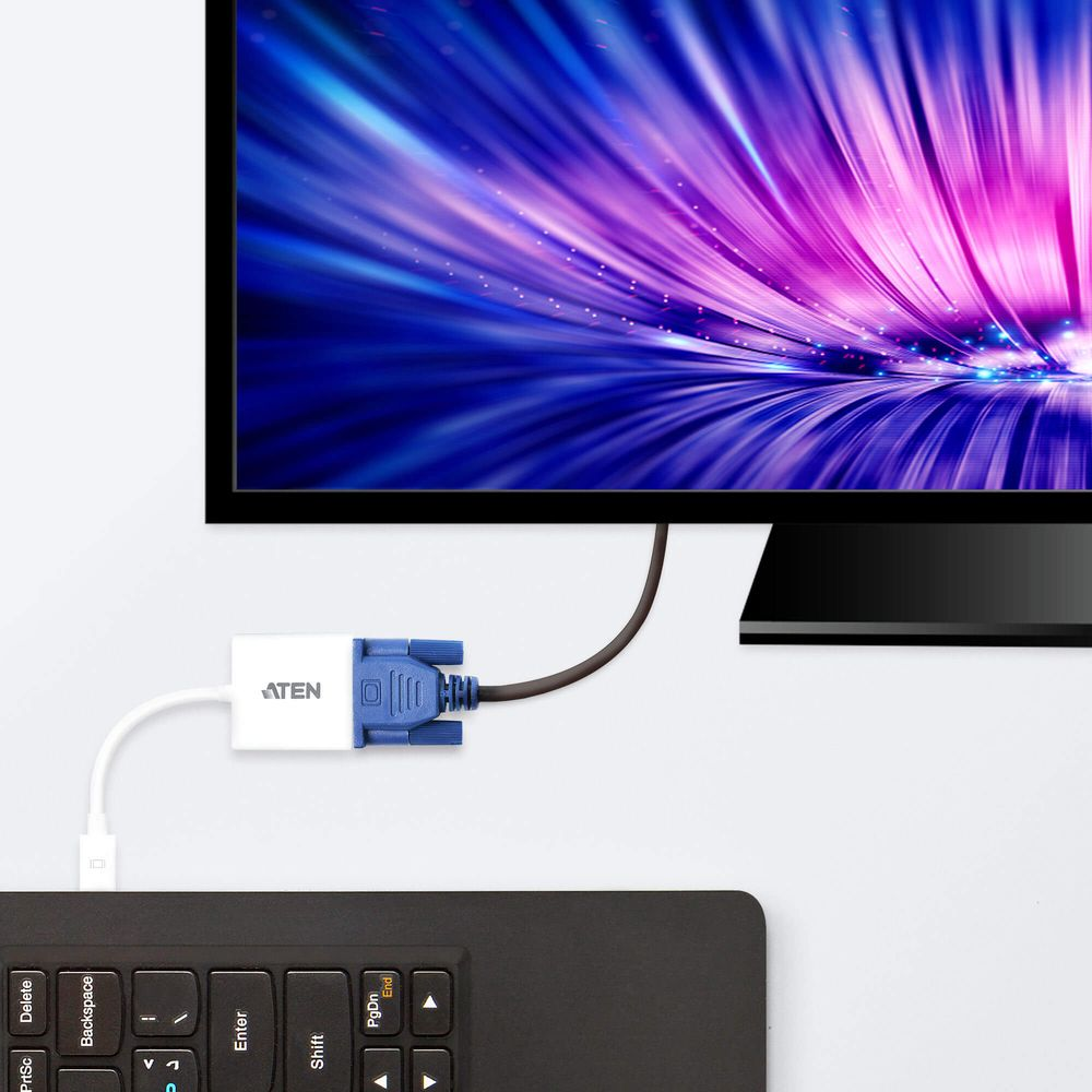 Un adaptateur ATEN blanc relie un clavier d'ordinateur portable à un moniteur affichant une vague abstraite.