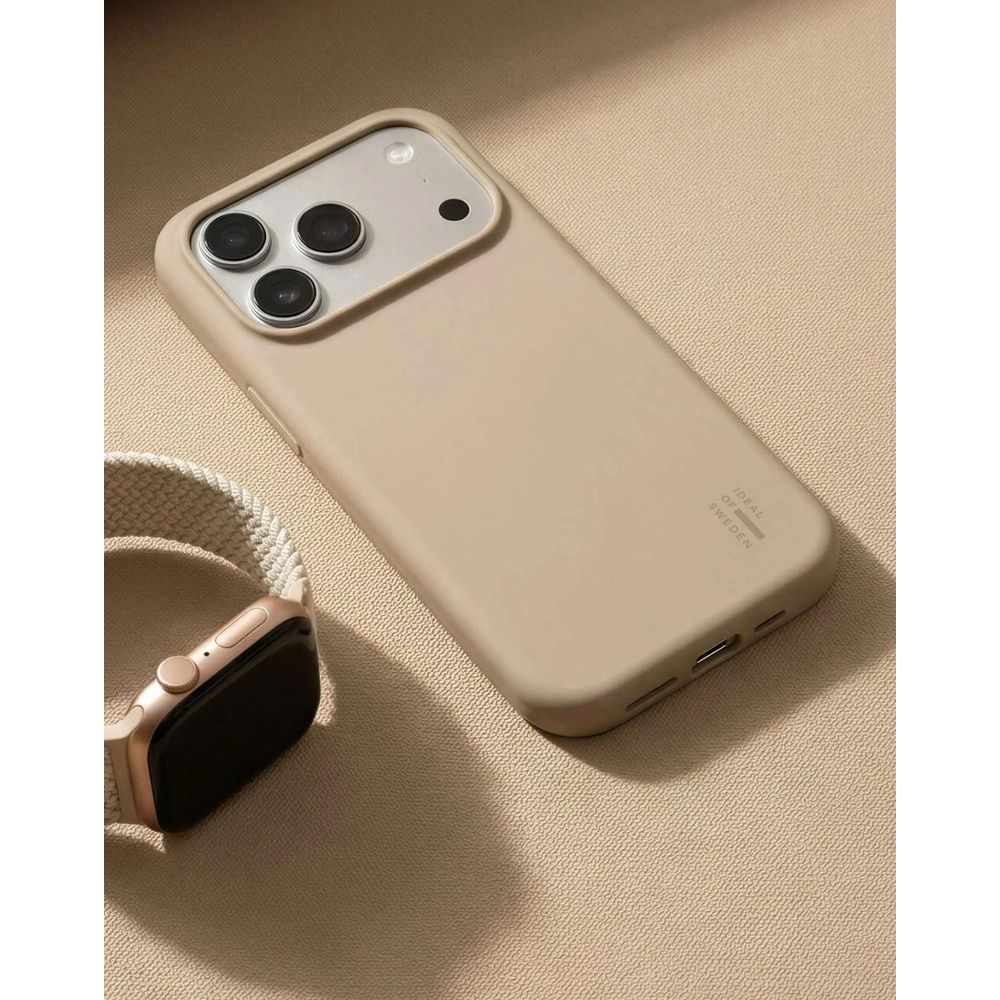 Una custodia per telefono beige e uno smartwatch abbinato con cinturino intrecciato giacciono su una superficie testurizzata.