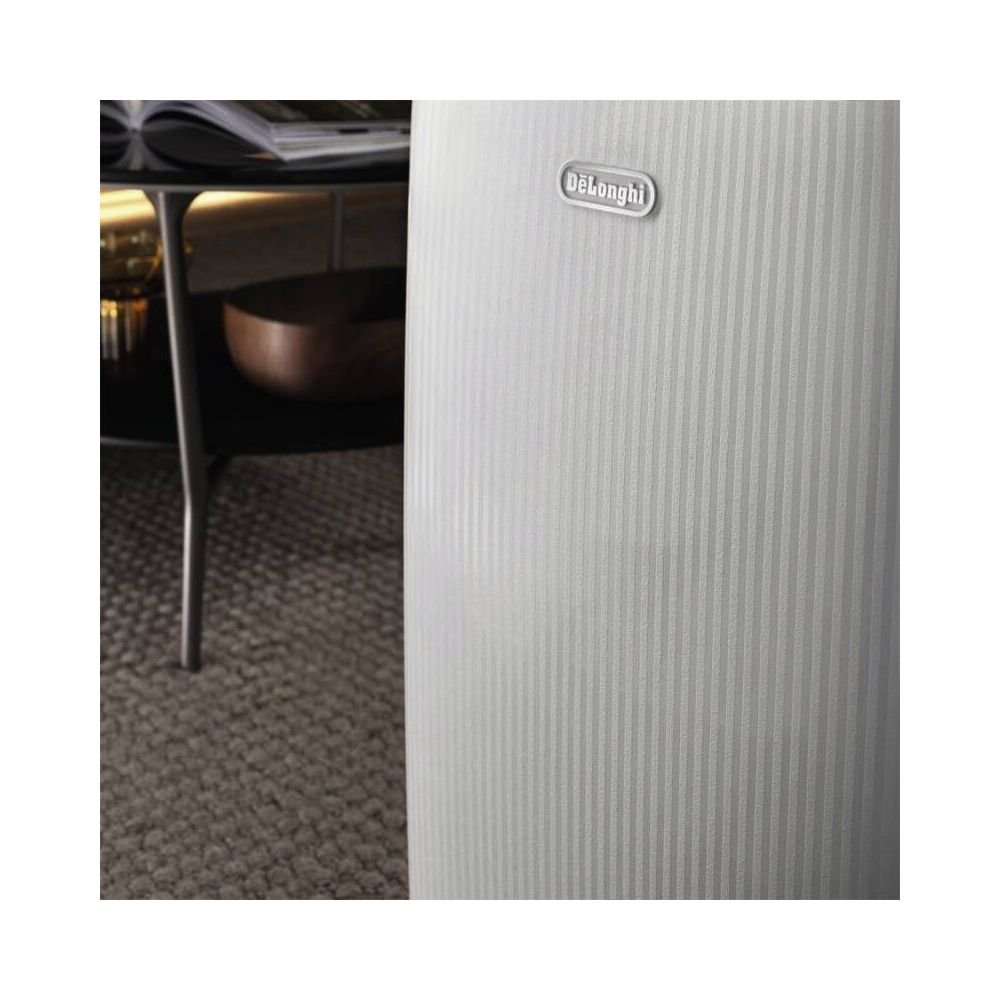 Superficie blanca y acanalada del aparato DeLonghi en una acogedora habitación con mesa de centro y alfombra.