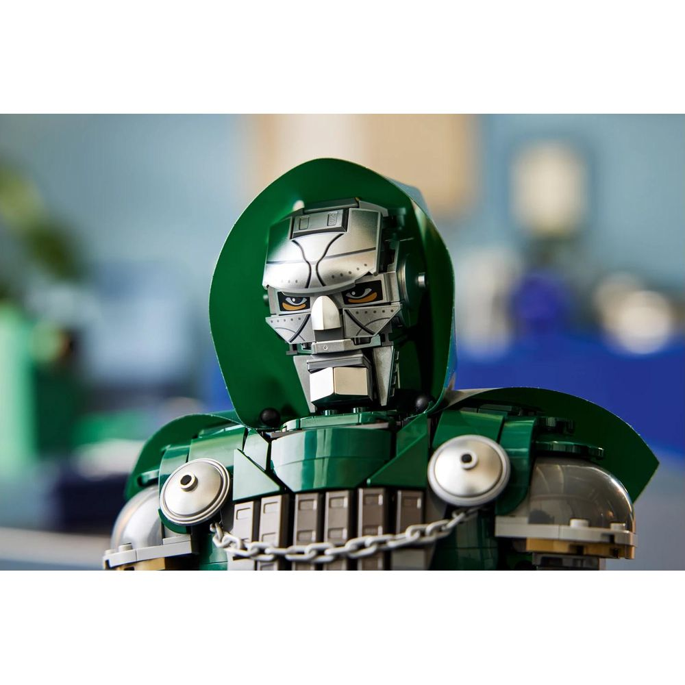 Metalik maskeli, yeşil kapüşonlu ve gümüş zincirli zırha sahip Lego Doctor Doom büstünün yakın planı.
