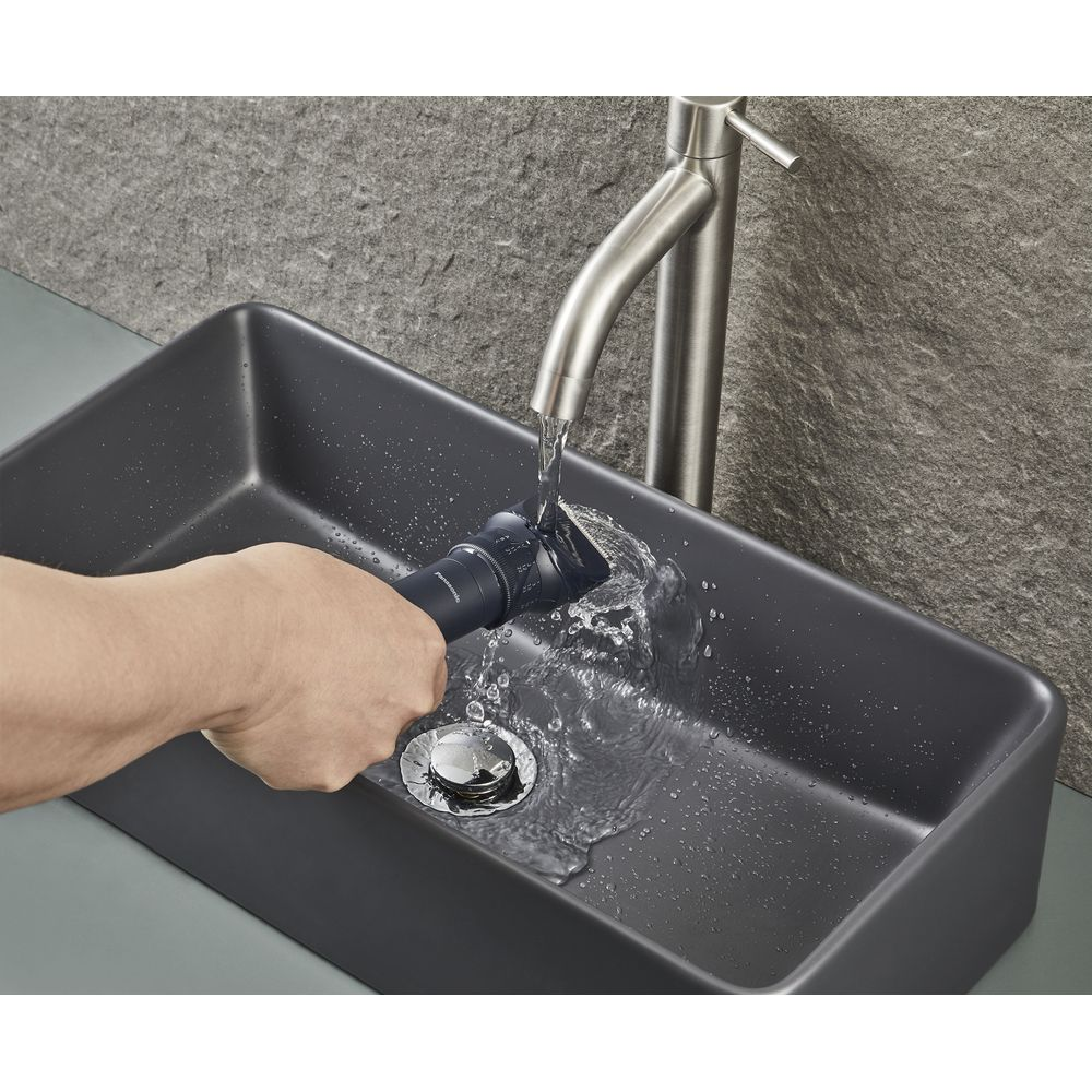 Una mano lava un rifinitore scuro sotto l'acqua corrente del rubinetto di un lavandino.