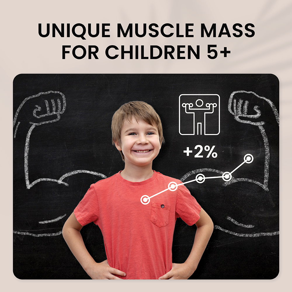 Smiling boy in a red t-shirt in front of a blackboard with muscle graphics.