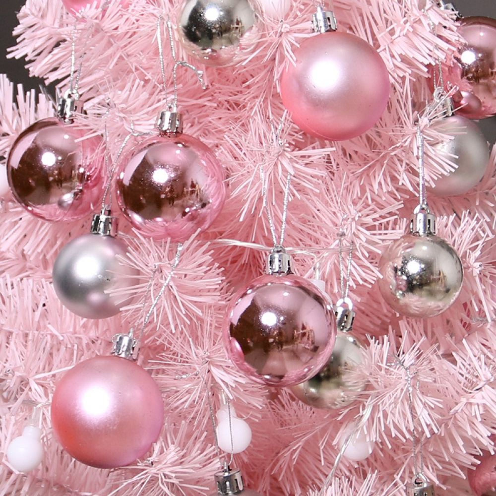 Ein kleiner rosa Weihnachtsbaum mit glänzenden rosa und silbernen Kugeln.
