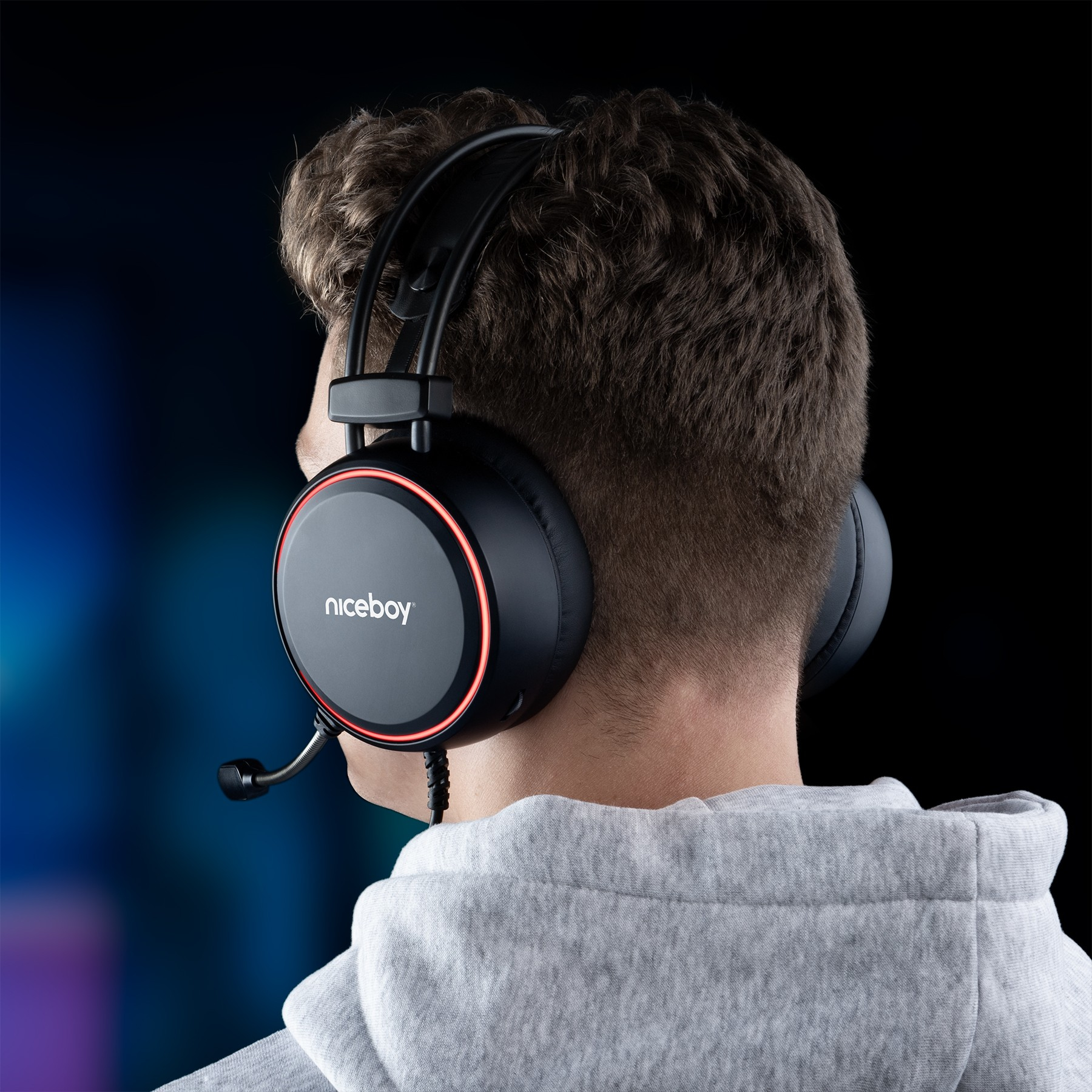 Ein junger Mann mit grauen Kapuzenpullover trägt schwarze Niceboy-Gaming-Kopfhörer mit rotem LED-Ring.