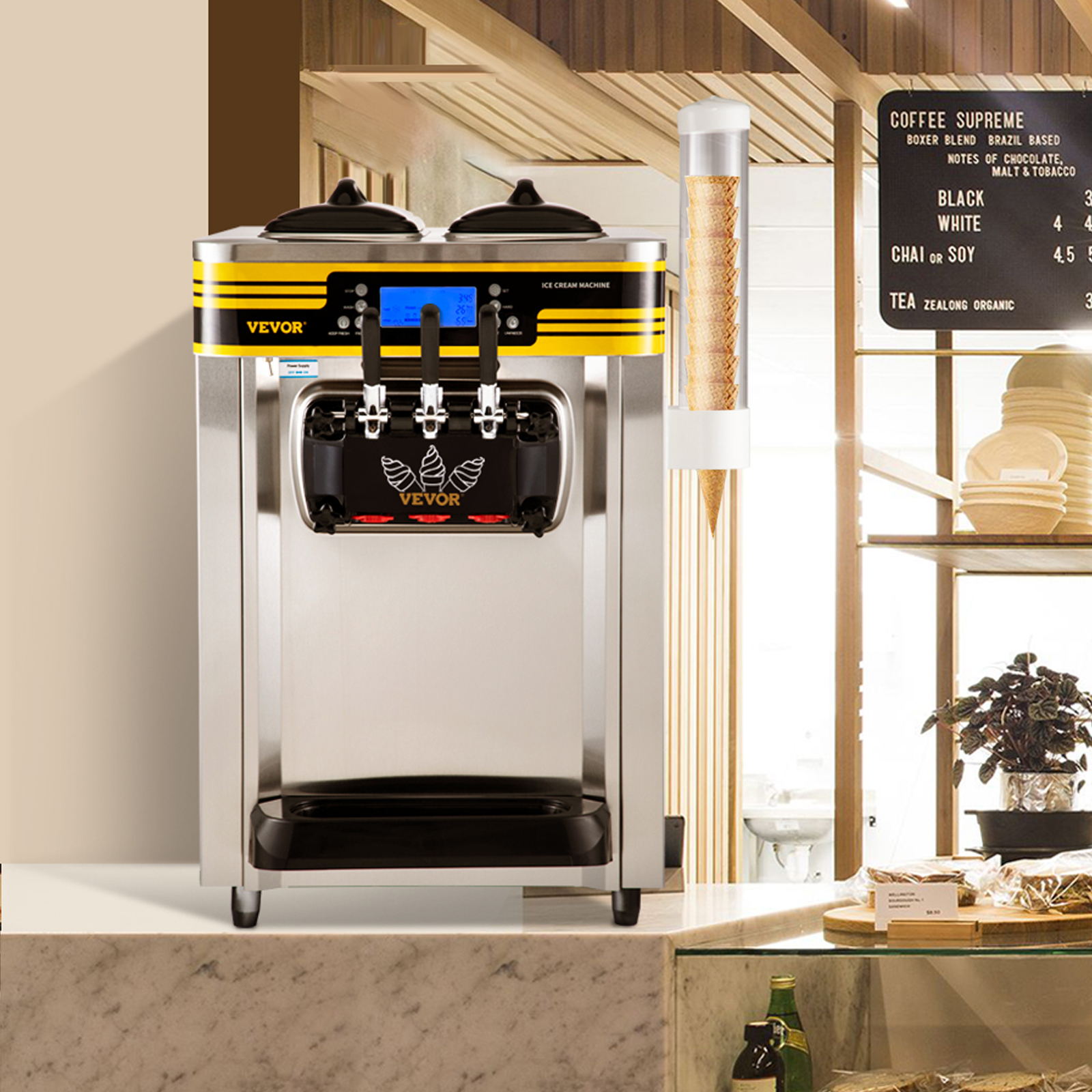 Máquina de helados de acero inoxidable con tres dispensadores y franja amarilla en una barra de café.