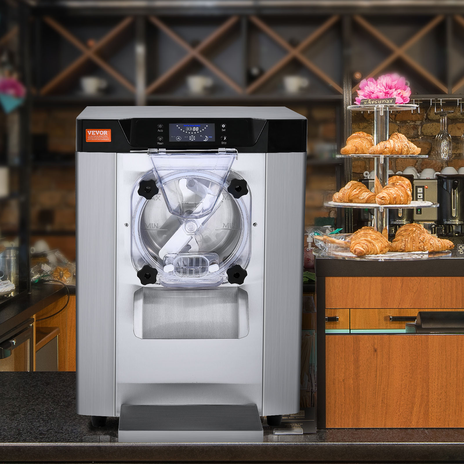 Una máquina de helados Vevor plateada en un mostrador de cafetería con cruasanes y estantes detrás.
