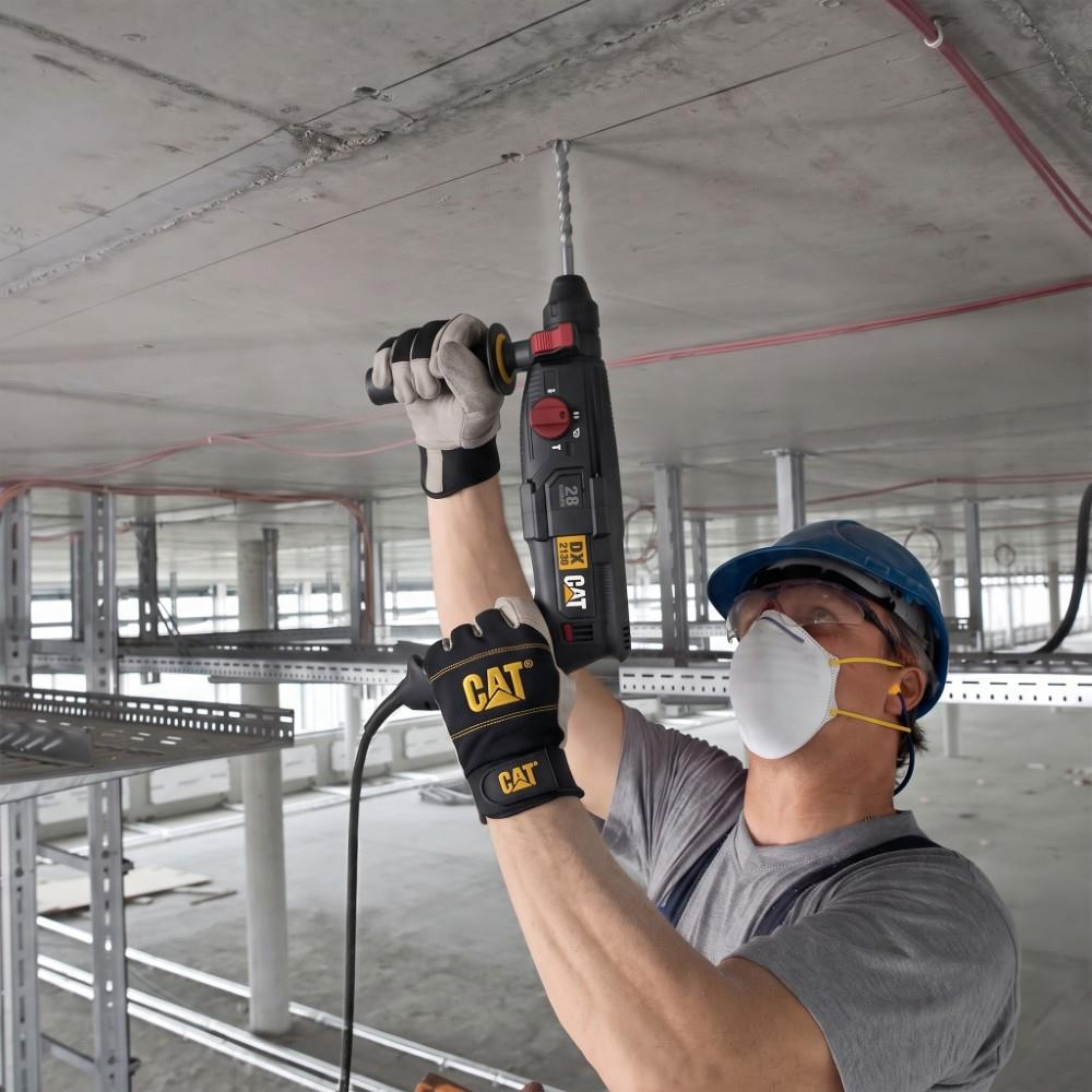 Güvenlik ekipmanlı bir işçi içeride beton tavana CAT kırıcı delici ile delik açıyor.