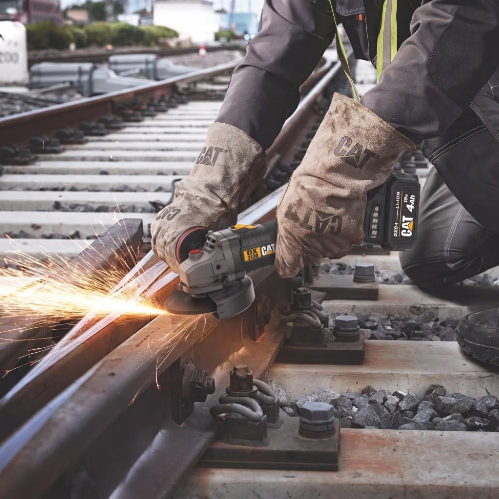 Koruyucu giysili bir işçi tren raylarında taşlama makinesi kullanarak kıvılcım çıkarıyor.