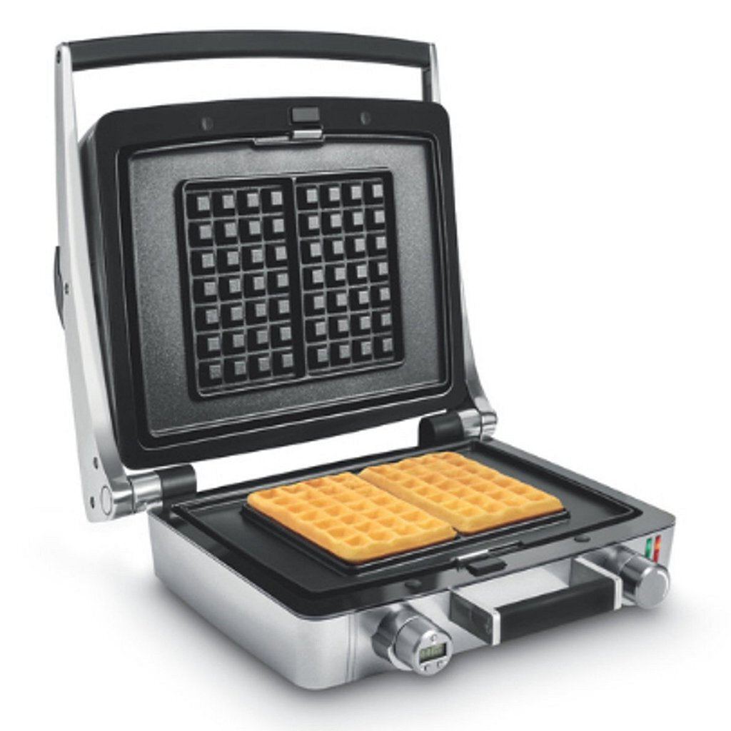 Una piastra per waffle argentata aperta con due waffle dorati appena sfornati sulla piastra inferiore.