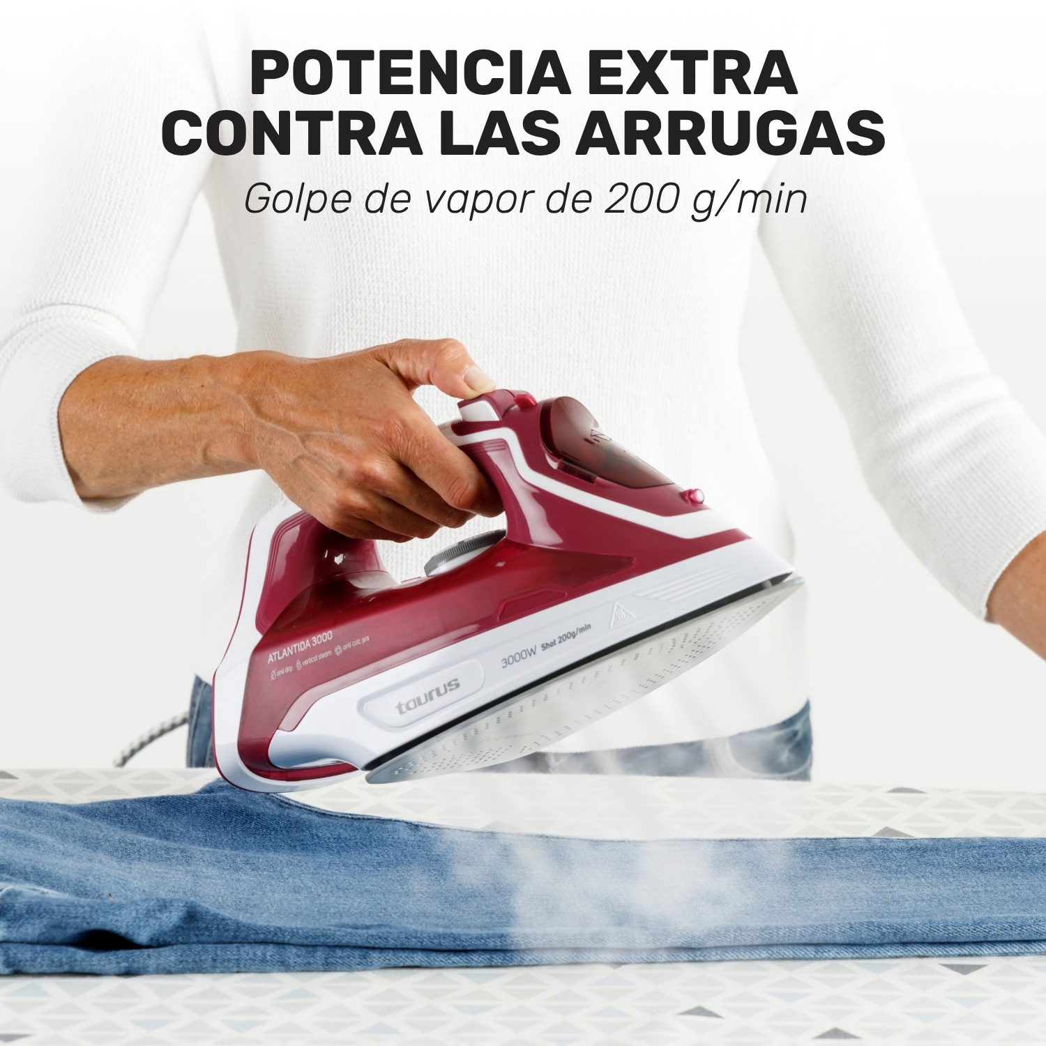 Una persona sosteniendo una plancha roja y blanca Taurus aplicando vapor en unos vaqueros.