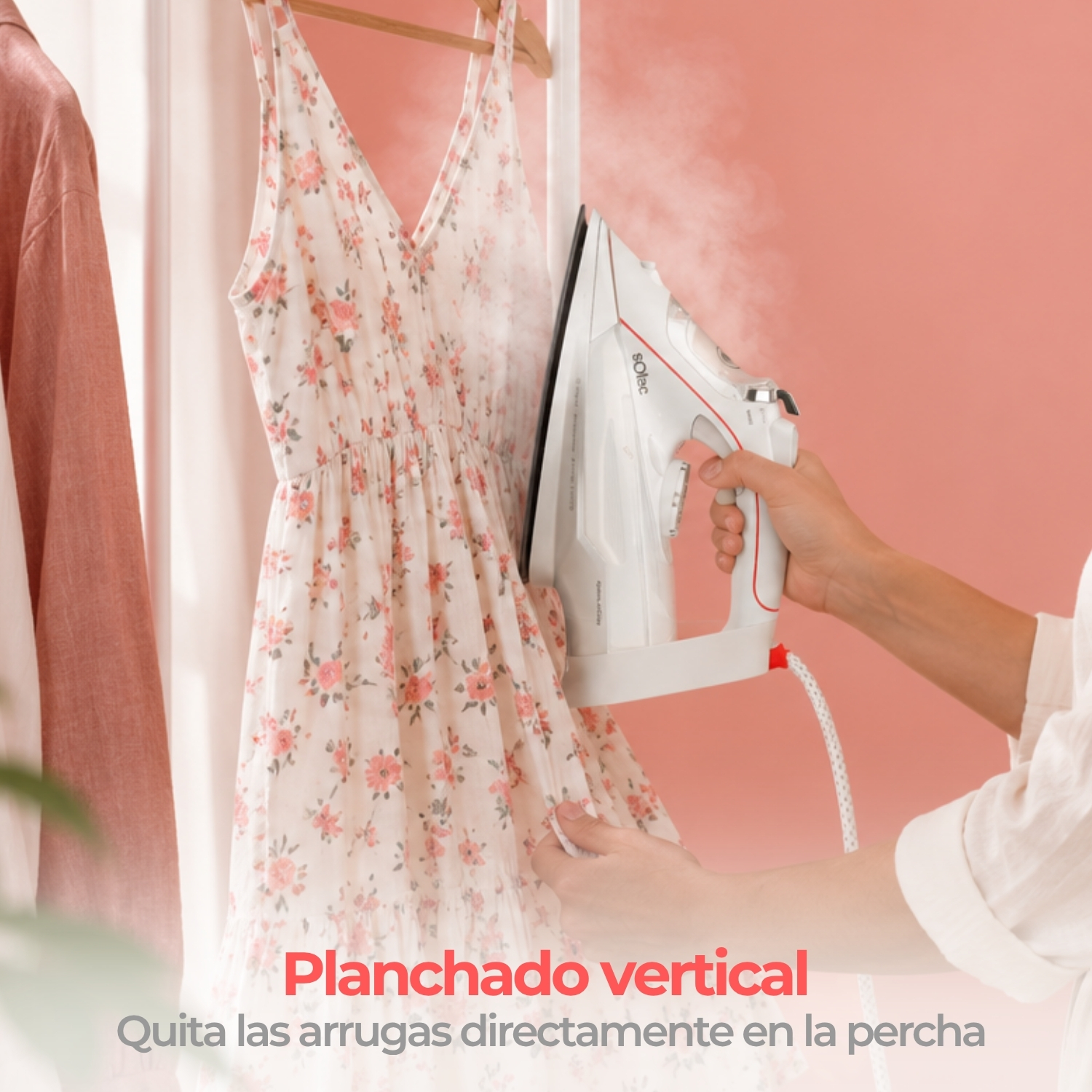 Una plancha blanca emite vapor sobre un vestido floral que cuelga de una percha.