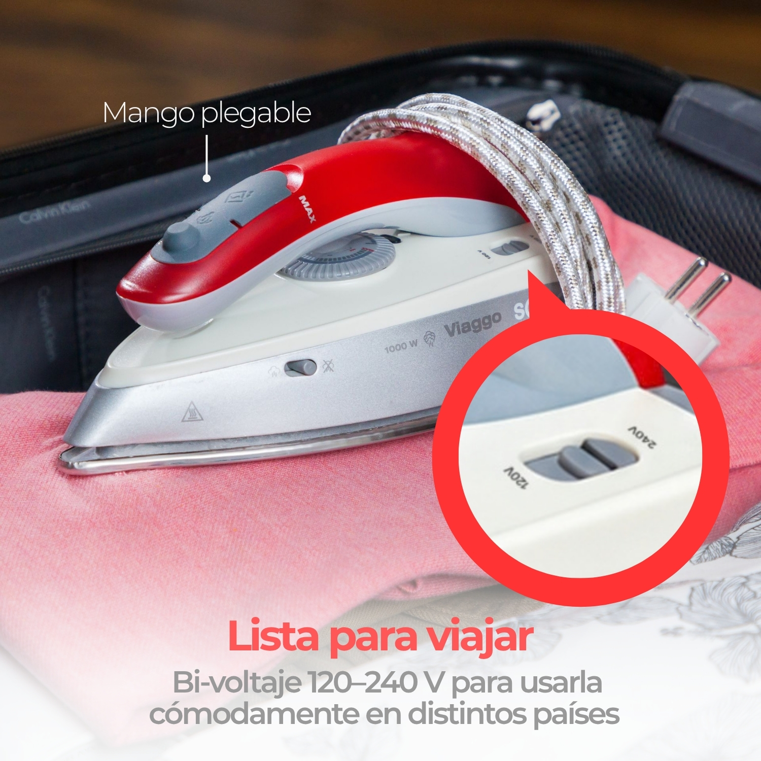 Plancha de viaje roja y blanca sobre ropa rosa en una maleta.