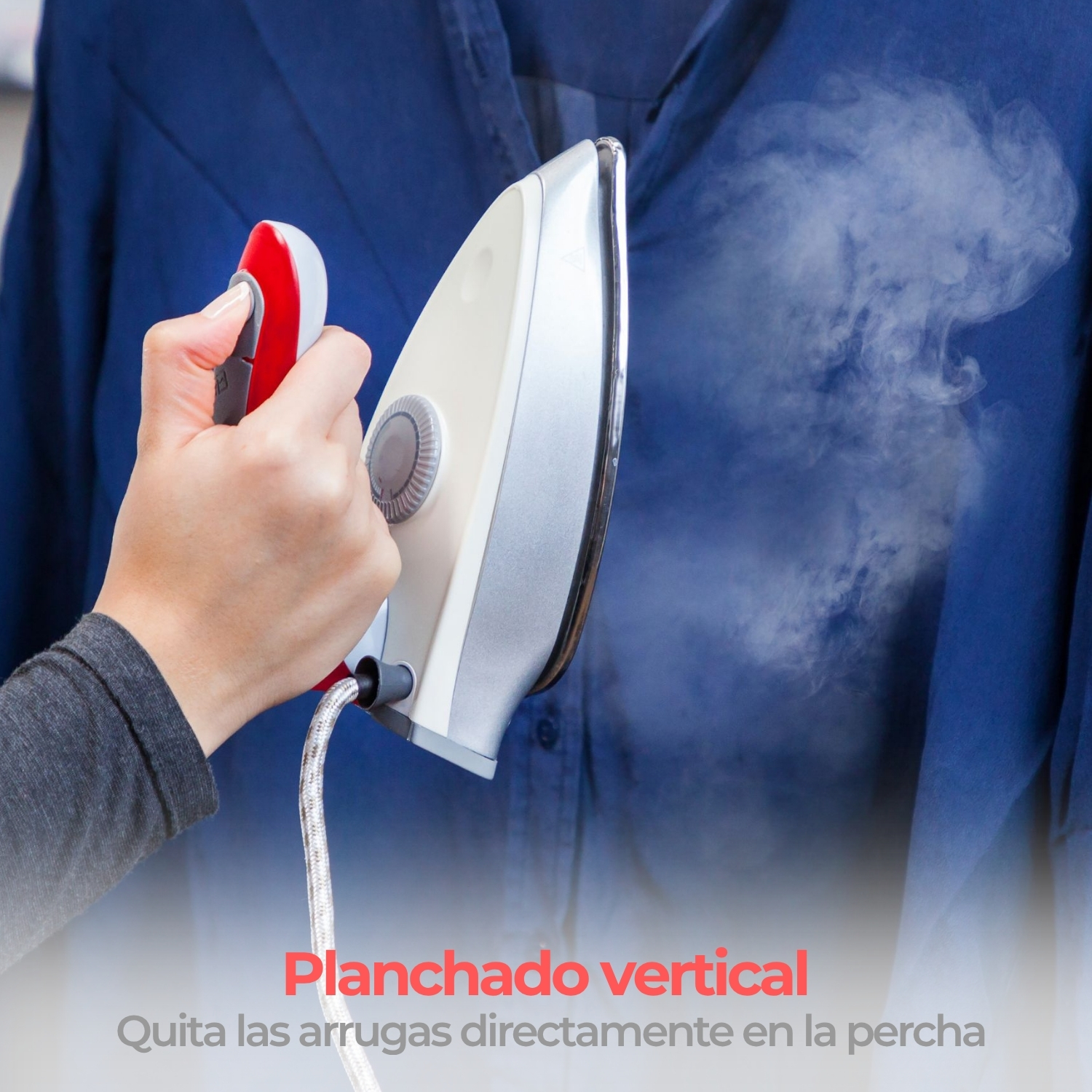 Una mano sostiene una plancha de vapor que emite vapor sobre una camisa azul.