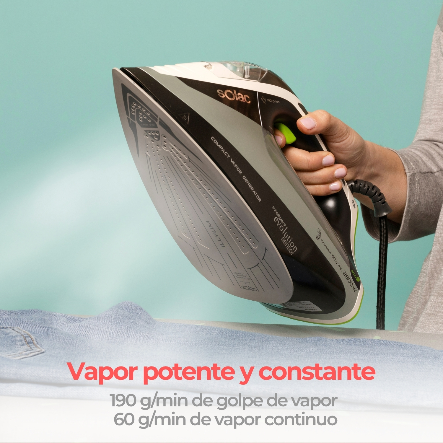 Mano sostiene una plancha de vapor Solac gris sobre jeans azules con fondo azul claro y texto.
