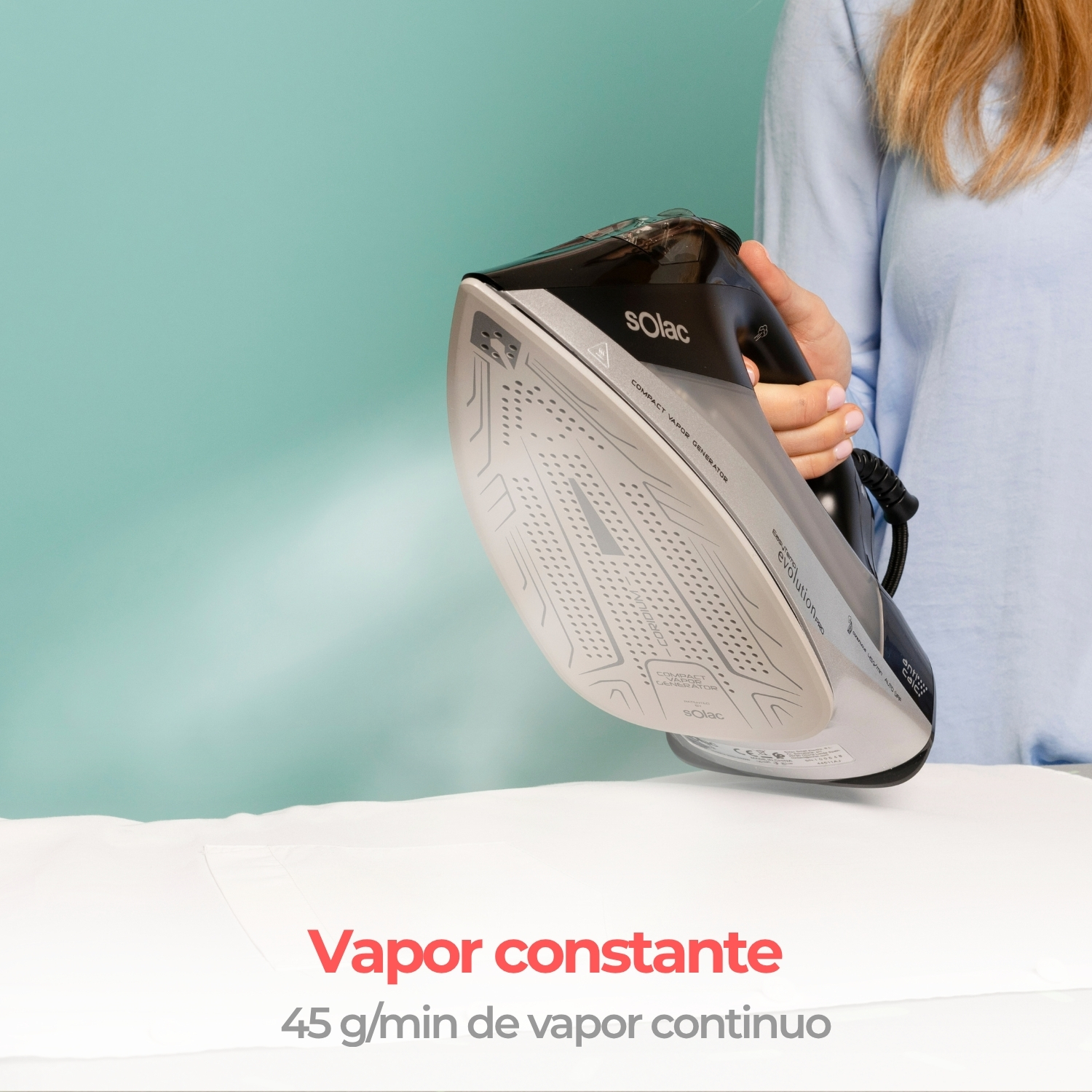 Persona sostiene una plancha de vapor Solac sobre un paño blanco, emitiendo vapor.