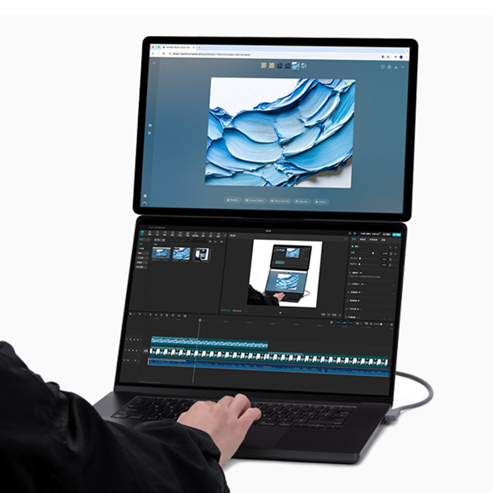 Użytkownik pisze na klawiaturze laptopa z dwoma ekranami, wyświetlającego niebieską grafikę i montaż wideo.