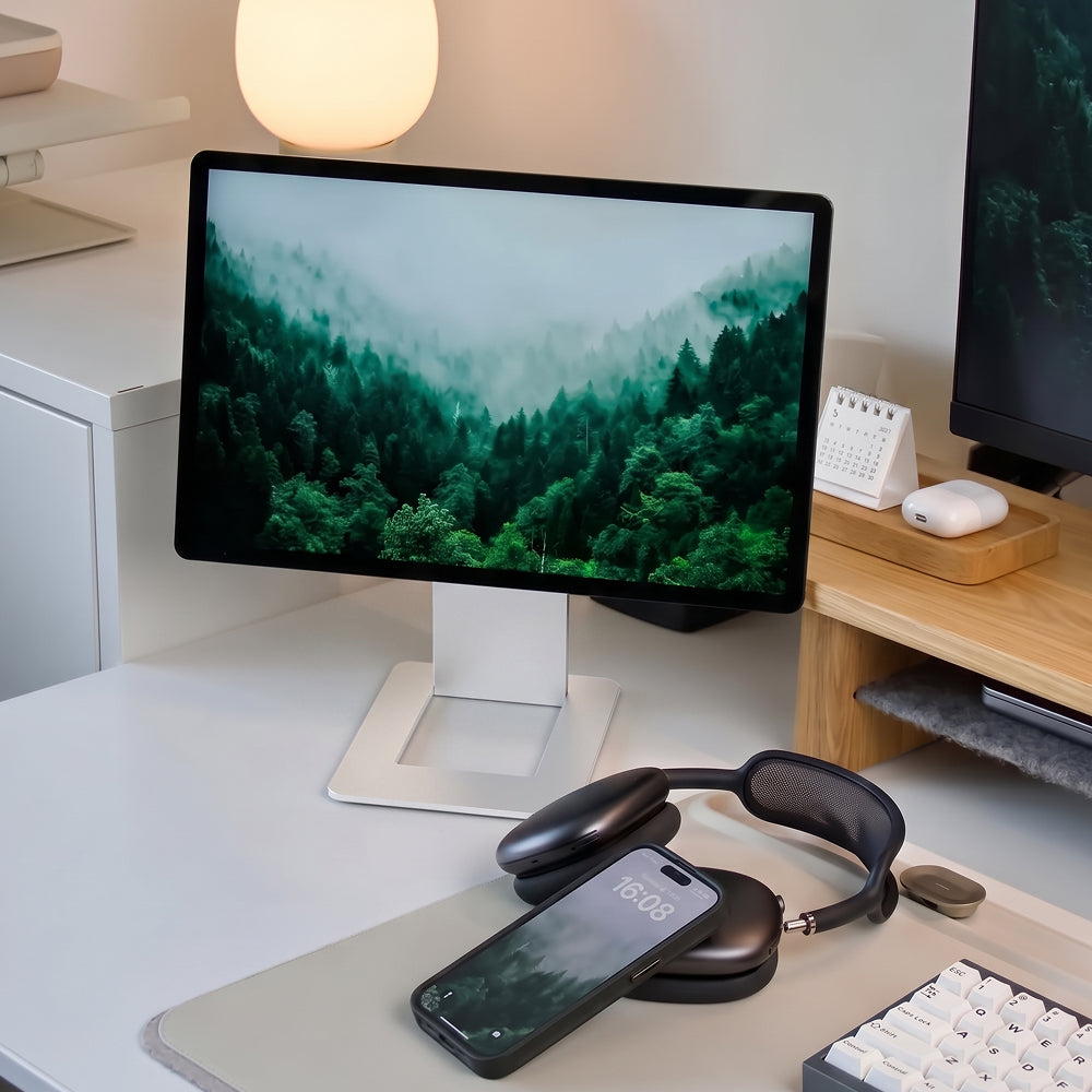 Czyste biurko z monitorem z mglistym lasem, słuchawkami i smartfonem.
