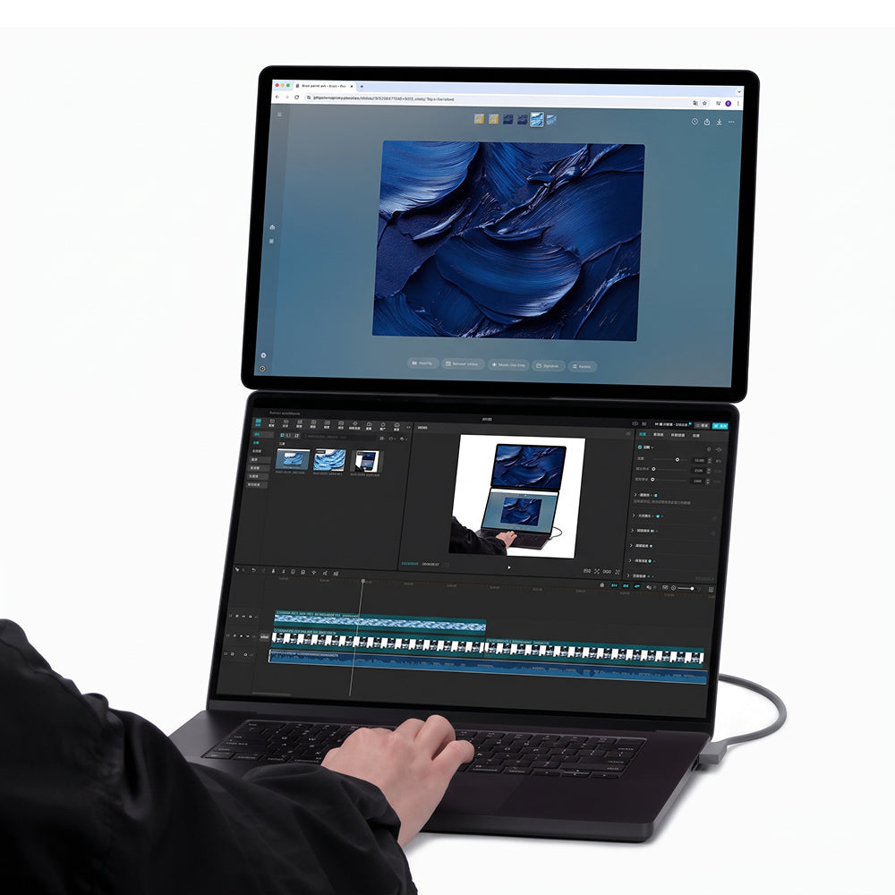 Un usuario escribe en el teclado de un portátil único de doble pantalla que muestra arte abstracto azul.