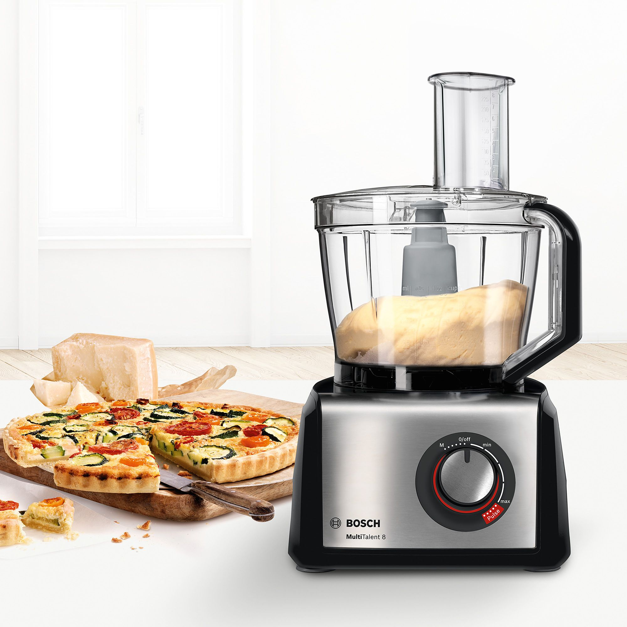 Procesador de alimentos Bosch MultiTalent 8 con masa, con quiche y queso en una tabla de madera.