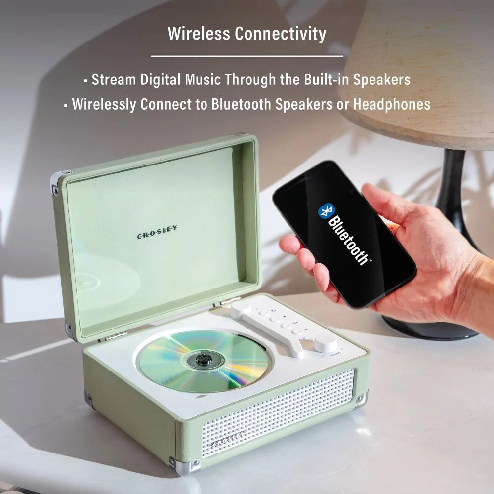 Ein grüner Crosley CD-Player mit Bluetooth-Smartphone und Lampe im Hintergrund.