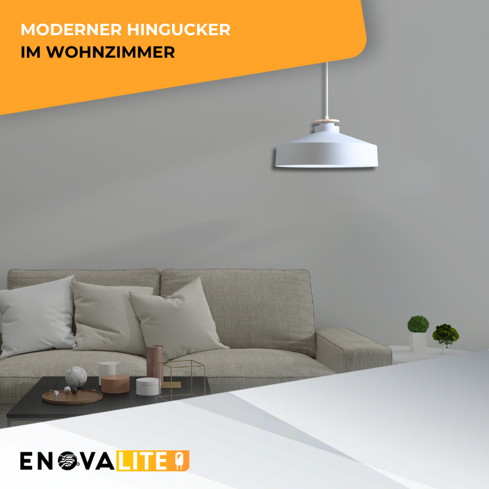 Moderne weiße Hängeleuchte über einem grauen Sofa mit Kissen, einem Kaffeetisch und grauer Wand.