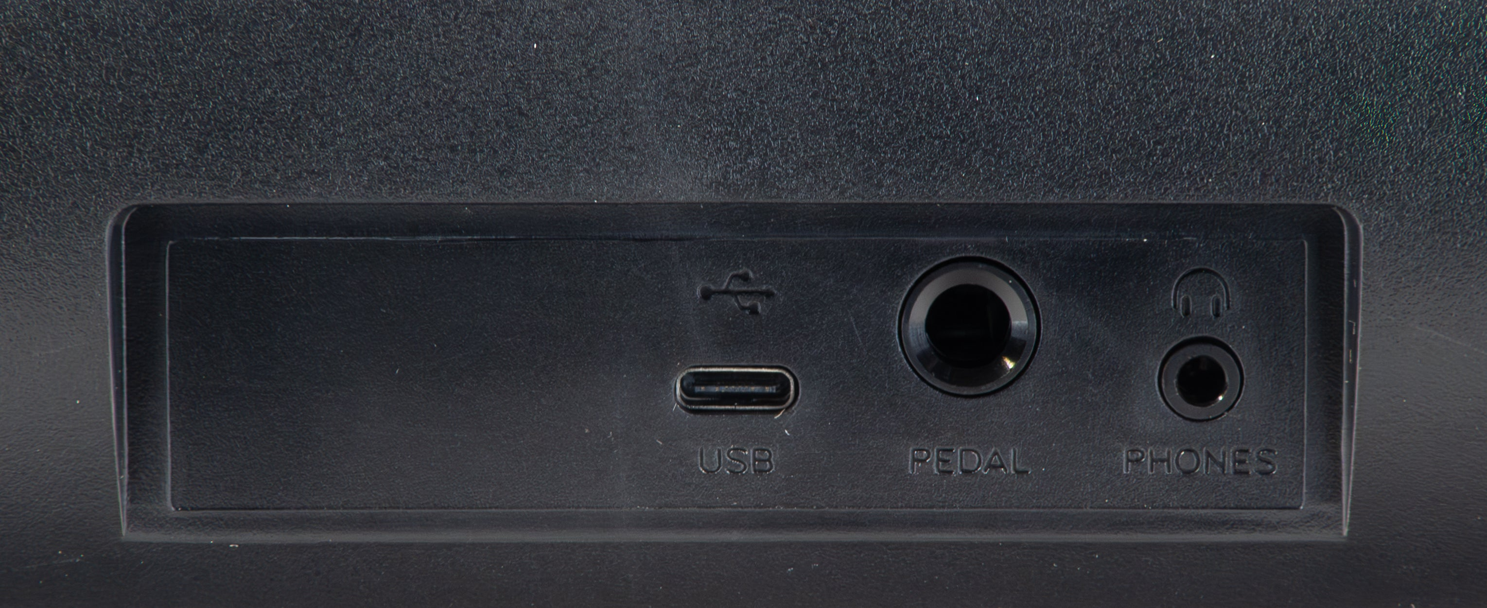 Rückseite eines schwarzen Geräts mit USB-, Pedal- und Kopfhöreranschlüssen.