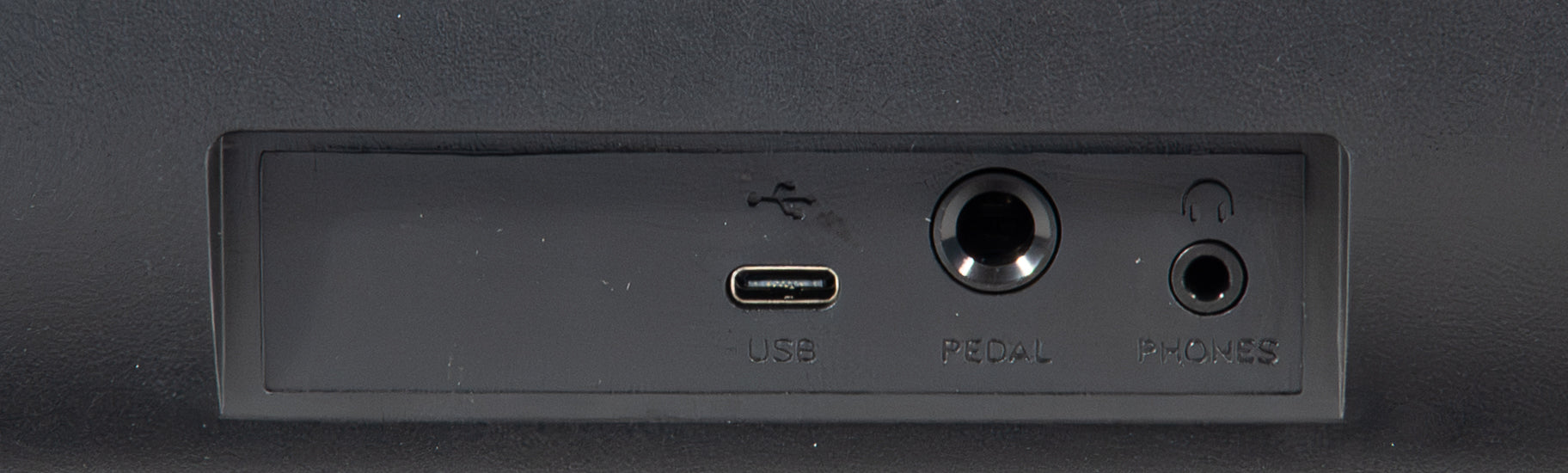 Rückseite eines schwarzen Geräts mit USB-C-Anschluss, Pedal- und Kopfhörerbuchse.