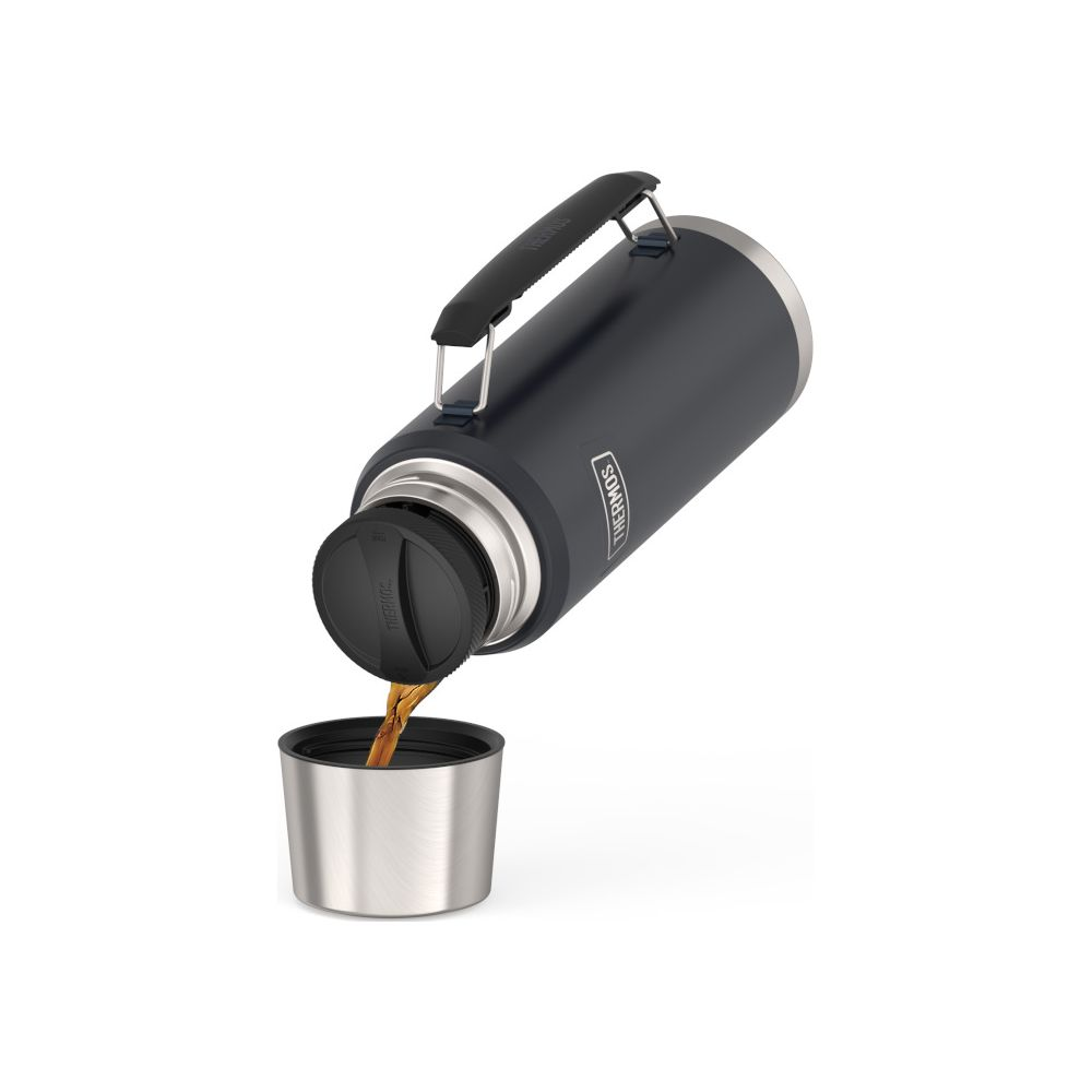 Eine schwarze Thermoskanne gießt Kaffee in einen kleinen Silberbecher vor weißem Hintergrund.