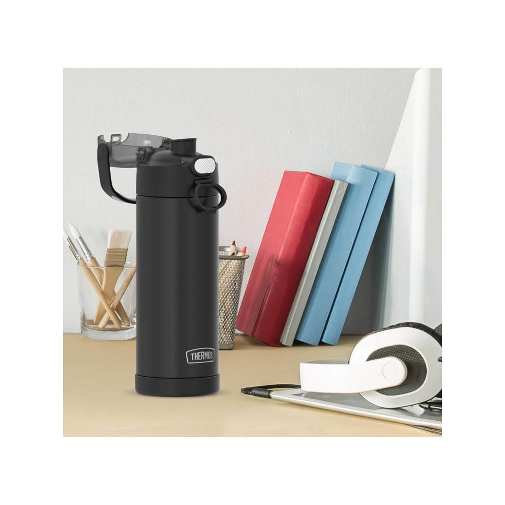 Eine schwarze Thermosflasche steht auf einem Schreibtisch neben Büchern, Stiften und Kopfhörern.