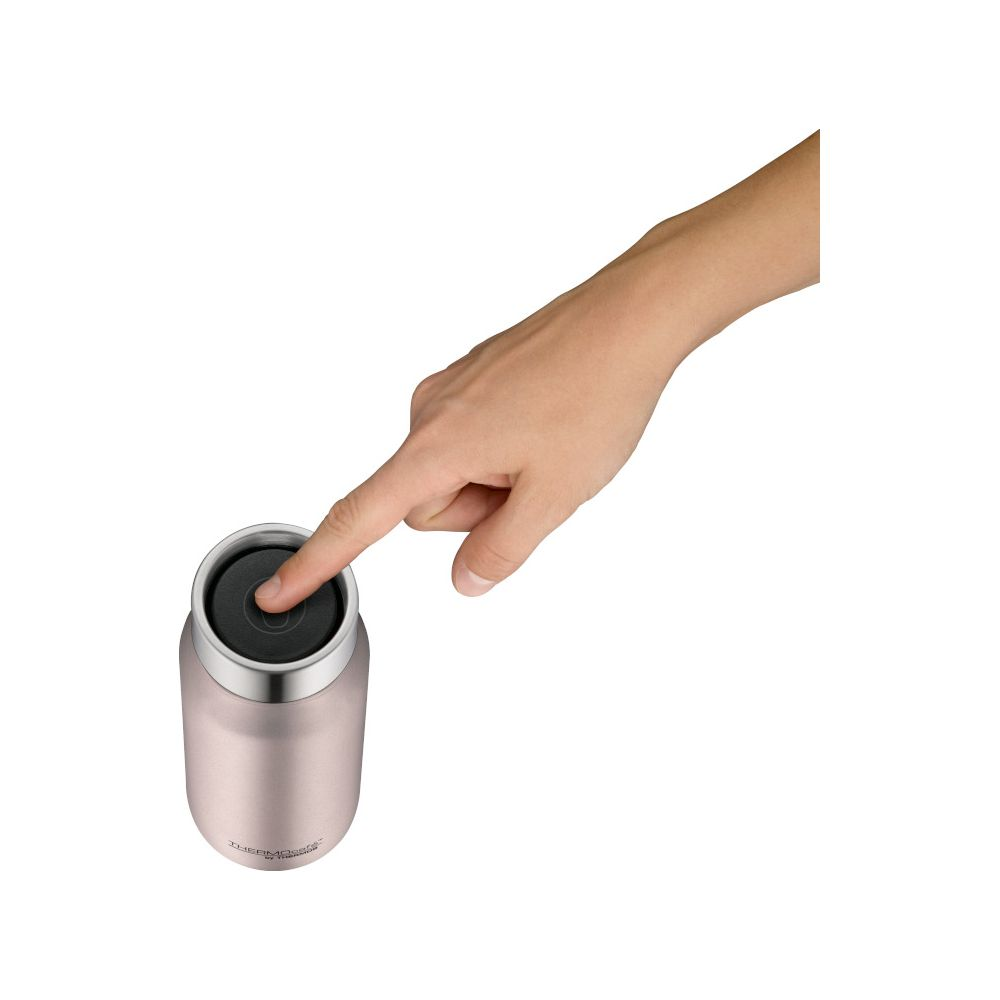 Eine Hand drückt auf den schwarzen Deckel einer rosa Thermoskanne.