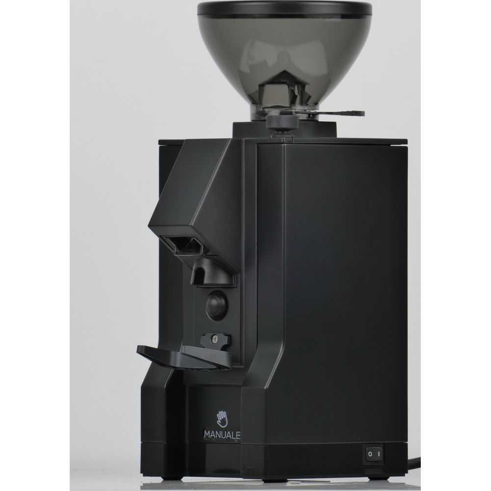Eine schwarze Kaffeemühle mit transparentem Bohnenbehälter auf weißer Oberfläche vor hellem Hintergrund.