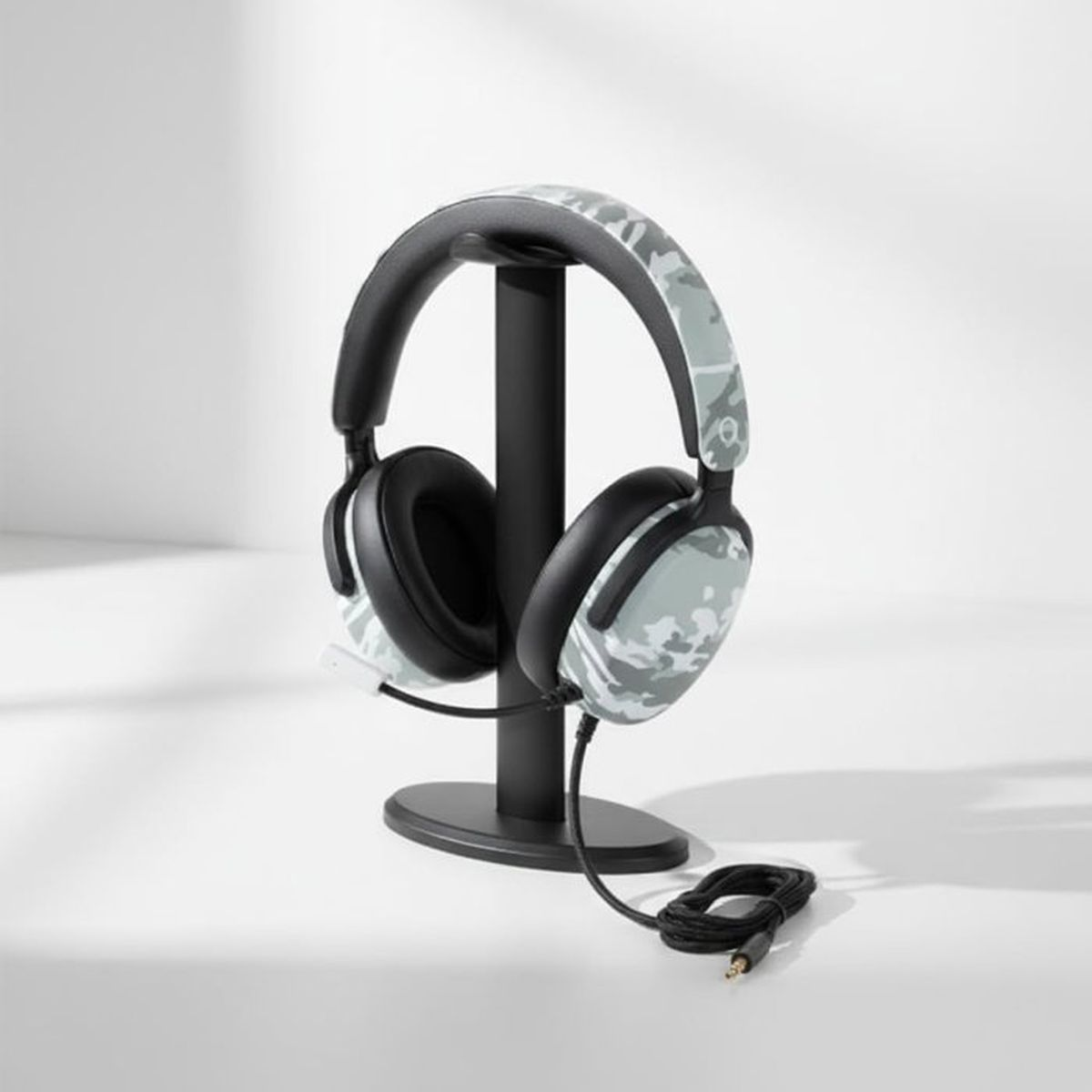 Cuffie da gioco camo grigie con microfono su supporto nero su sfondo bianco.