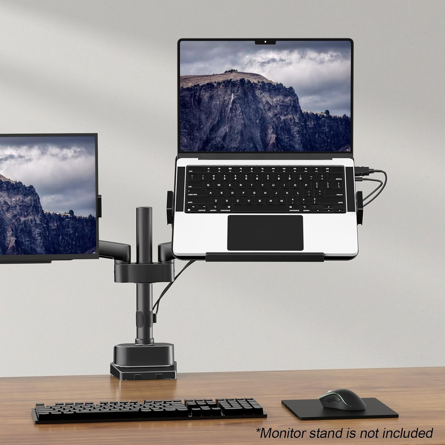 Ein Laptop und Monitor auf einem Schreibtischarmständer mit Tastatur und Maus auf einem Holztisch.